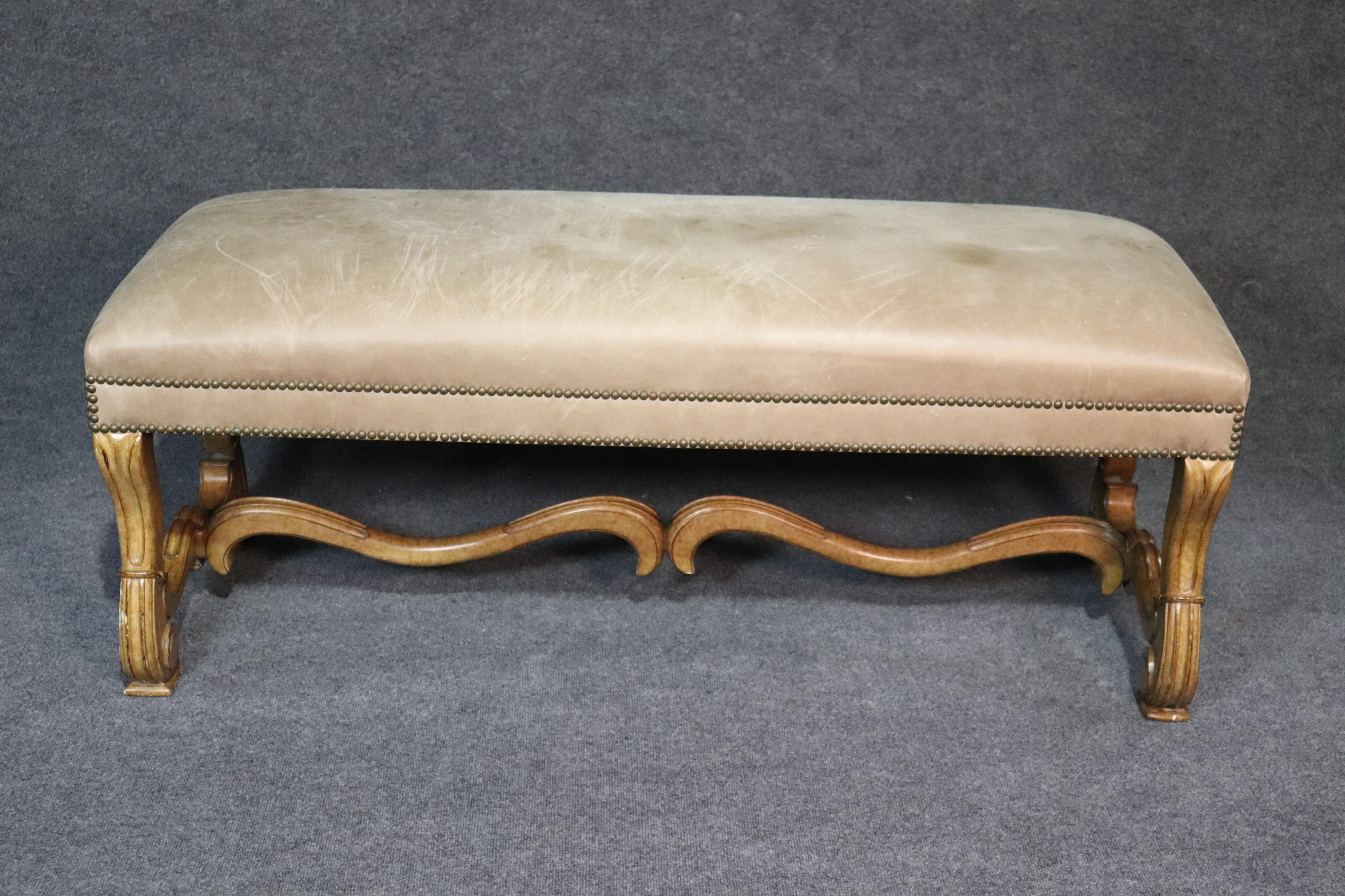 This is a stunning French style bench made in North Carolina. The bench has a rustic lacquer finish and a gorgeous time-worn aged leather surface with brass nail-head trim for a rustic and yet tailored appearance. The bench can be used at the foot