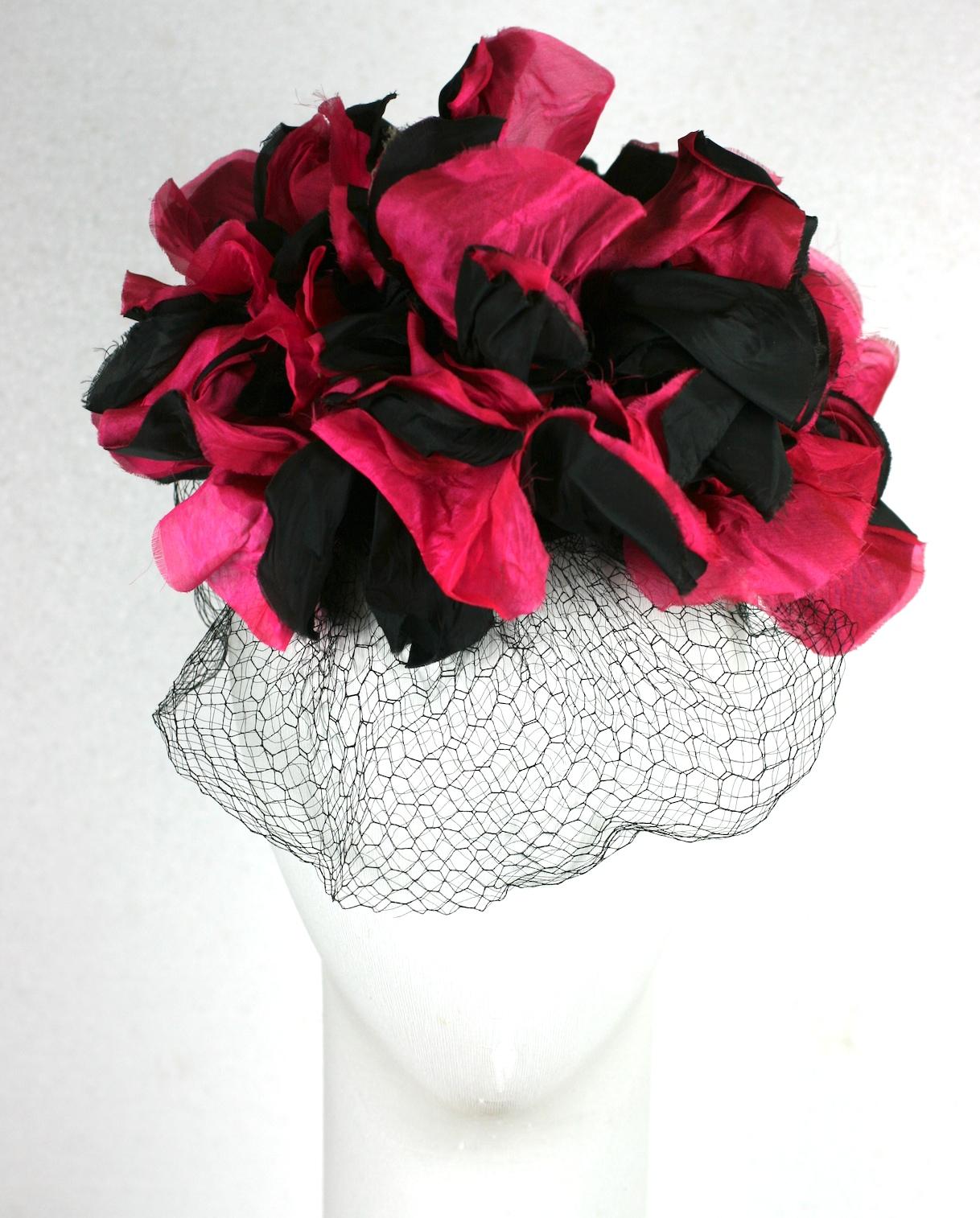 Dramatic Fuschia and Black Silk Flower Topper or Fascinator from the late 1930's. Large silky blooms perched on a tiny cap with self fabric wire covered hoop, elastic band and front silk veil. Retailed at Burdines, with original price tag.
Late