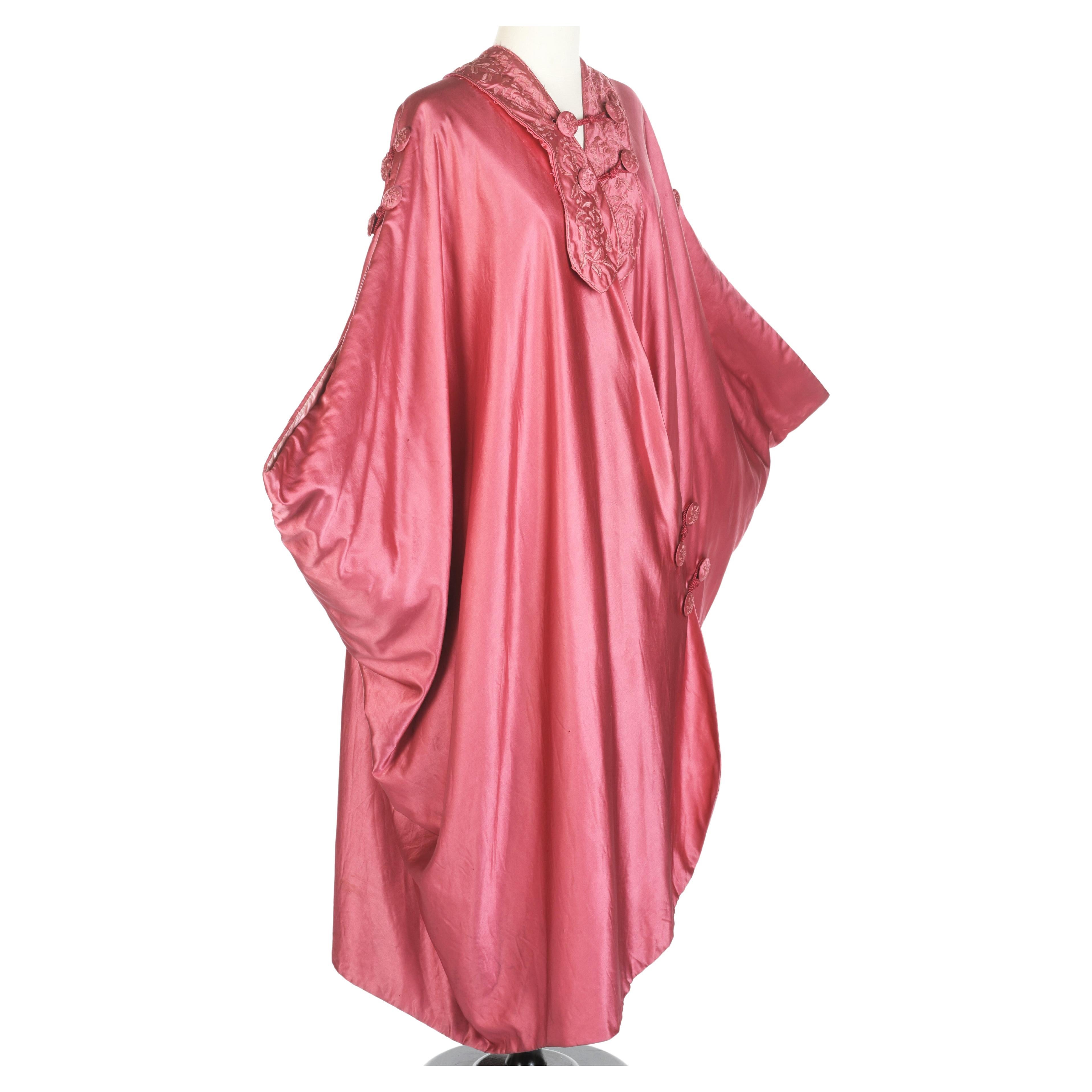 Circa 1915 - 1925
France for cutting
Asia Manila for the textile

Fuchsia pink embroidered satin evening cape attributed to Liberty of London, a famous British House Circa 1915/1925. Fleece cloak with side cross flap and large bonnet with tapered