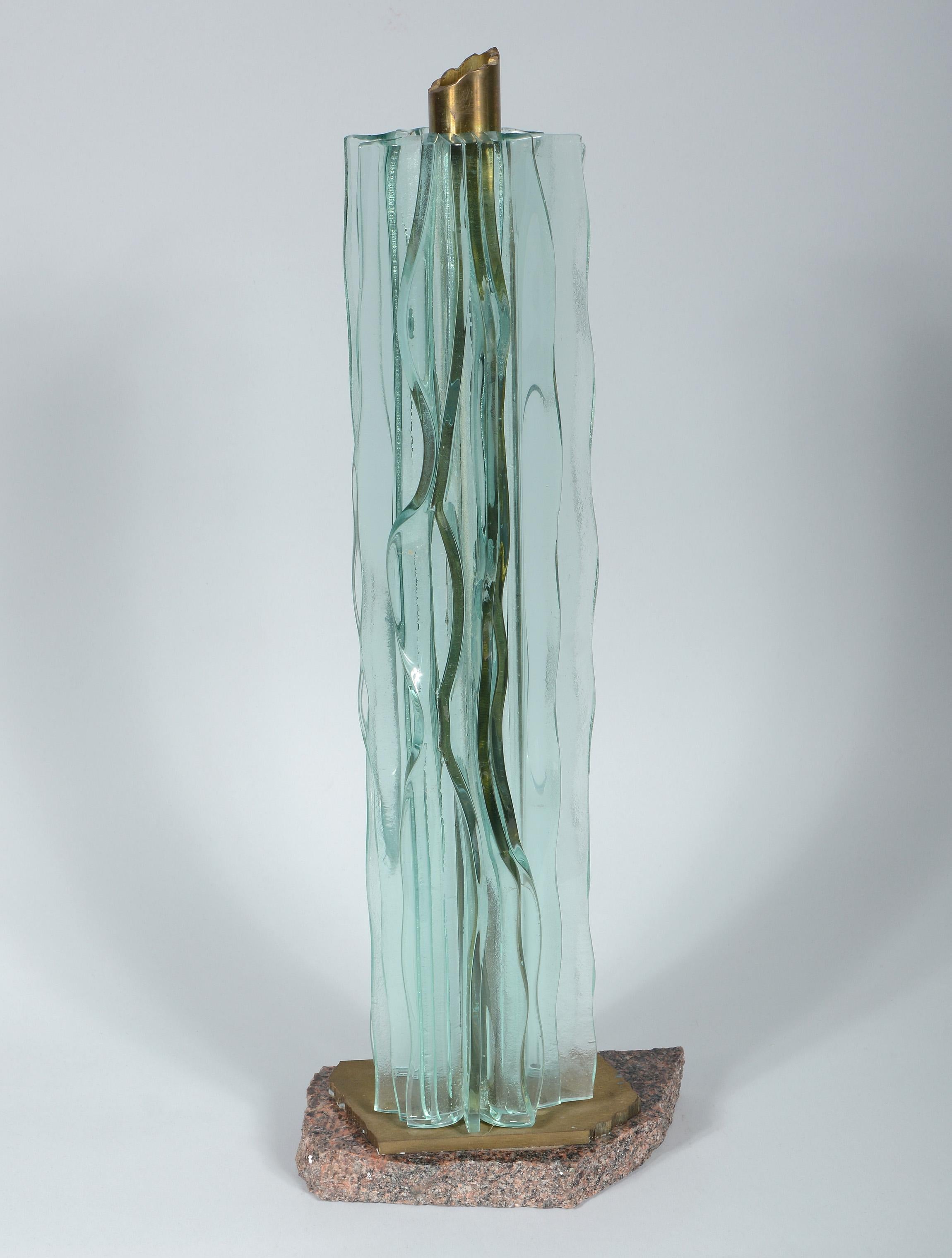 Tabletop sculpture by Seattle artist Nancy Mee. This has vertical undulating ribbons of fused glass around a column of bronze. The base is bronze and granite.
Nancy was born in Oakland, Calif. in 1951. She received a BFA in printmaking at the
