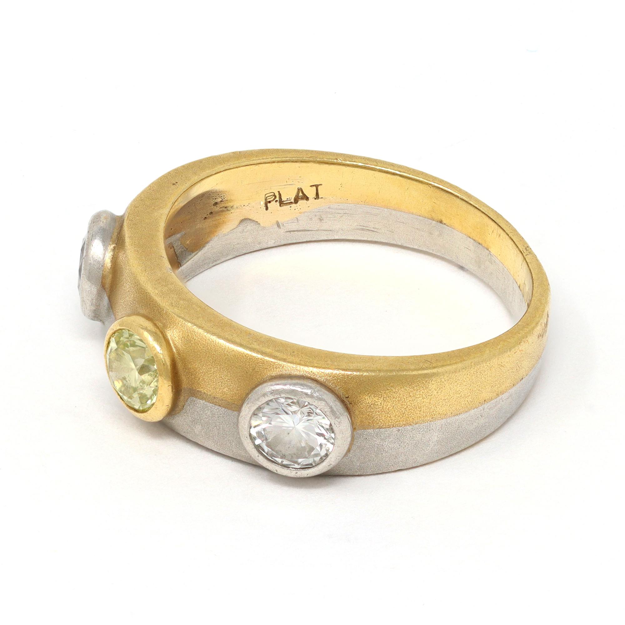 A 18 karat gold and platinum, white and fancy yellow diamonds band ring, designed as a platinum and yellow gold band fused together bezel-set at the front with 2 round white diamonds GH color VS clarity and 1 round fancy yellow diamond with a total