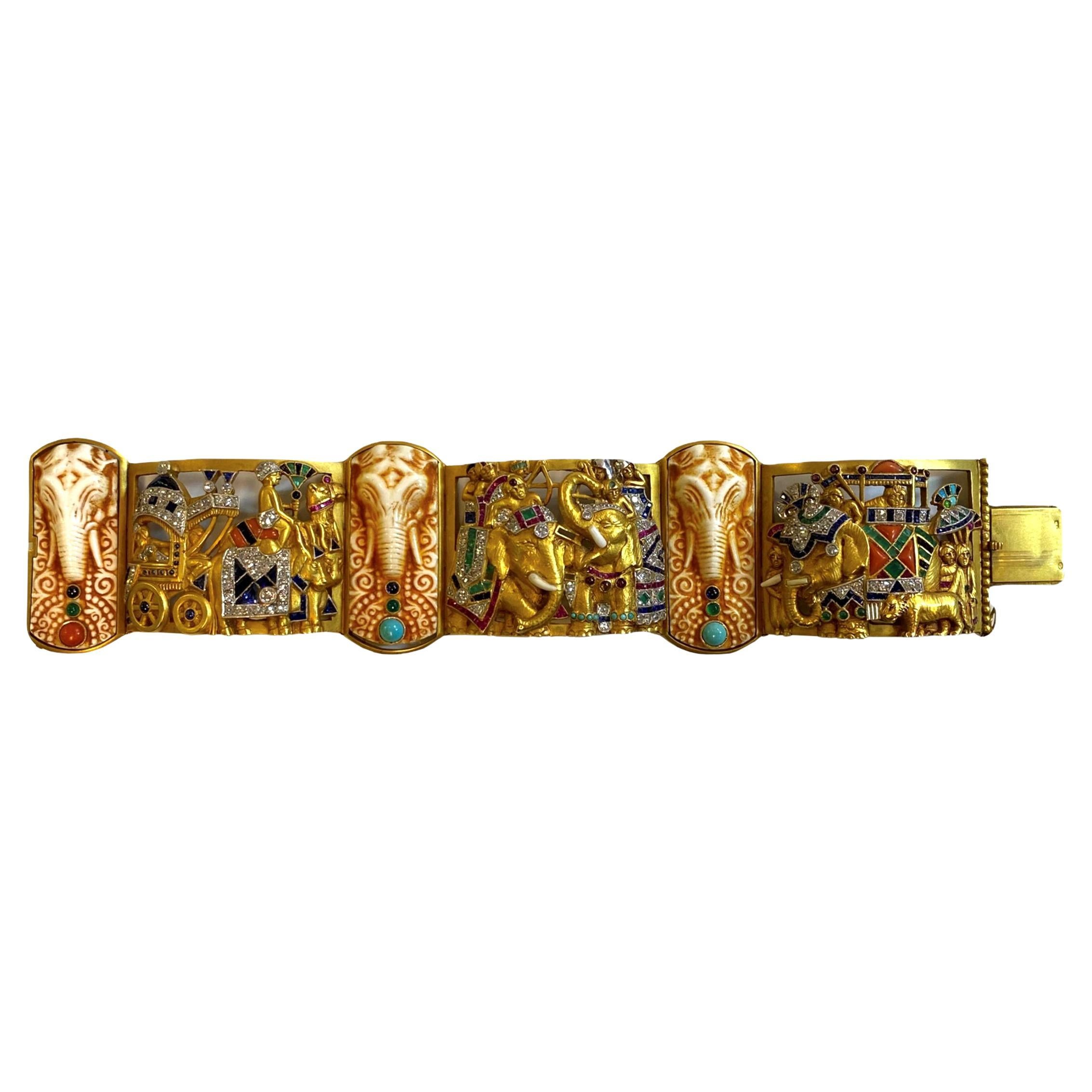 Unser außergewöhnliches Armband aus 18-karätigem Gold, mit Edelsteinen und Diamanten von Fuset y Grau, um 1930, zeigt eine zeremonielle Prozession des indischen Königshauses mit Reitern in Howdahs auf Elefanten, einer von Ochsen gezogenen Kutsche
