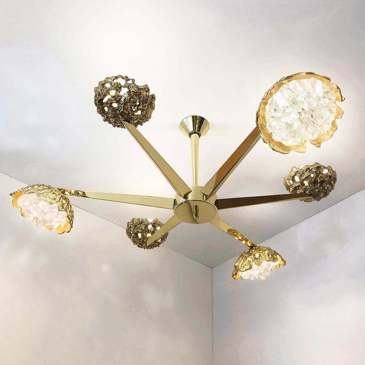 The Fusione ceiling fixture highlights the contrast between organic forms and sleek geometric lines; Cast brass shades with irregular glass crystals sprout from polished V shaped arms. The first images show the fixture in our polished brass