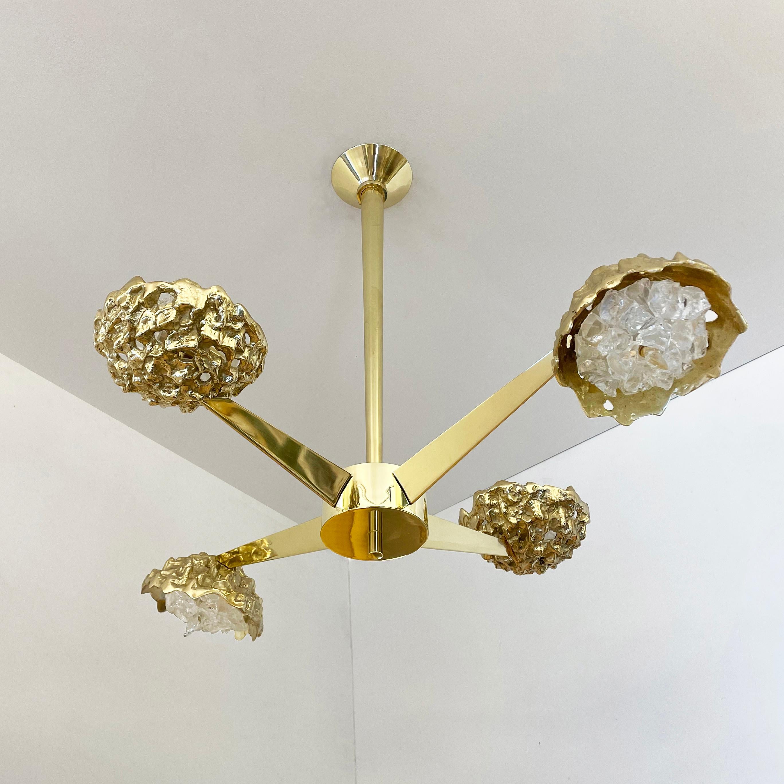 The Fusione N.4 ceiling fixture highlights the contrast between organic forms and sleek geometric lines; Cast brass shades with irregular glass crystals sprout from polished V shaped arms. Shown in polished brass with clear glass. See the Fusione