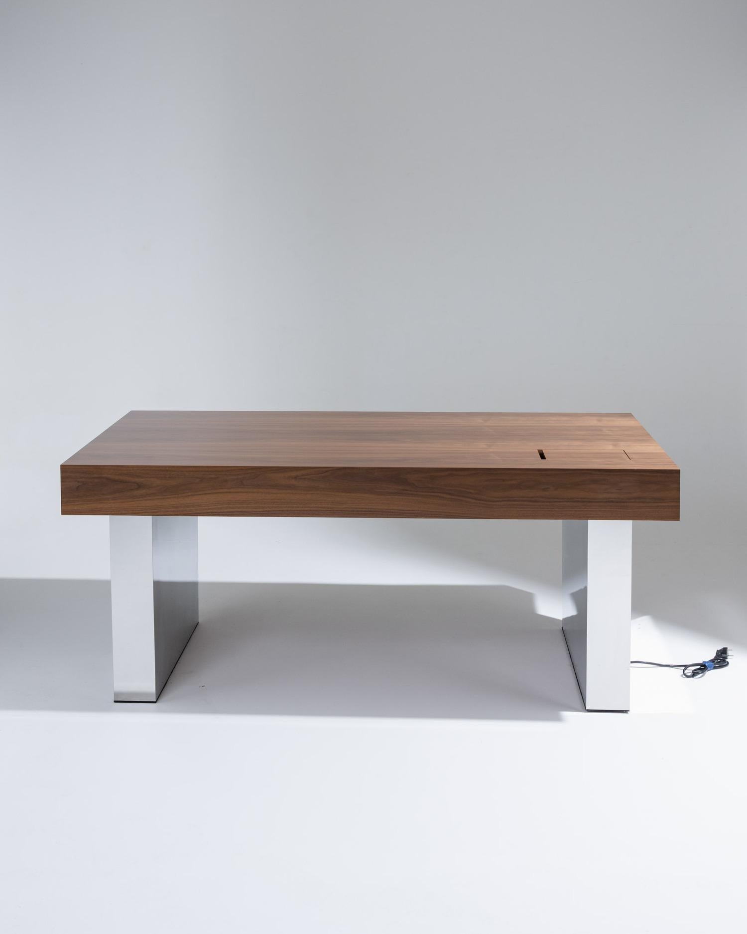 The “Futur” desk by Alma Ébénistes features a walnut top paired with a polished mirror-finish stainless steel base.
This elegant and contemporary piece combines the warmth of fine wood craftsmanship with the sleek precision of metalwork, reflecting