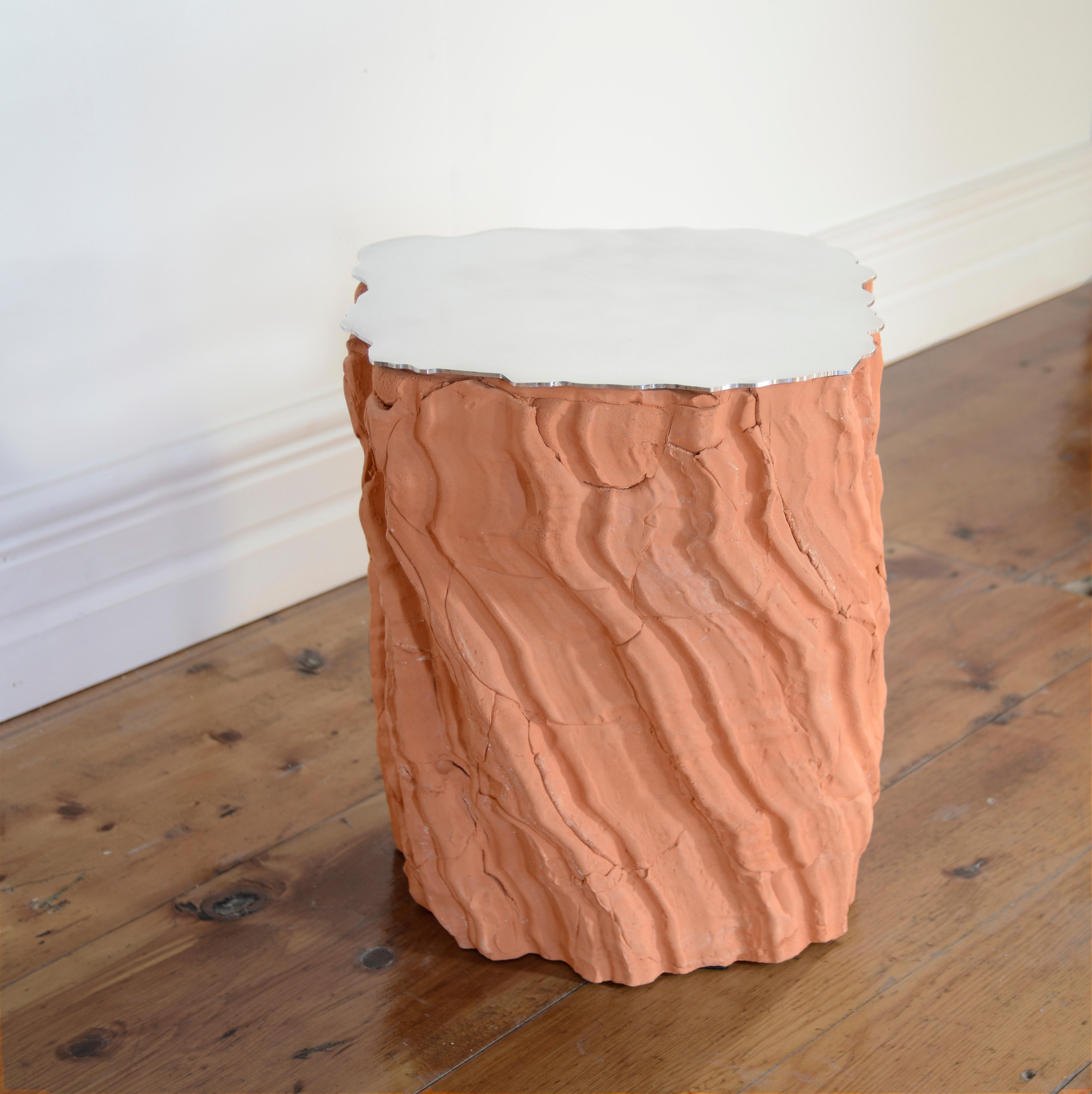 Future Fossils End Table is the result of hand pressing slabs of clay into a plaster mold, using the collections texture. The cracks and defects of this type of assembly remain visible on the outside and randomly interfere with the main texture.