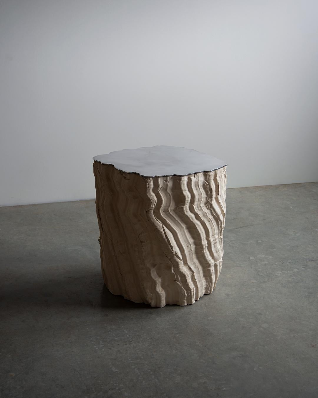 Future Fossils End Table is the result of hand pressing slabs of clay into a plaster mold, using the collections texture. The cracks and defects of this type of assembly remain visible on the outside and randomly interfere with the main texture.
