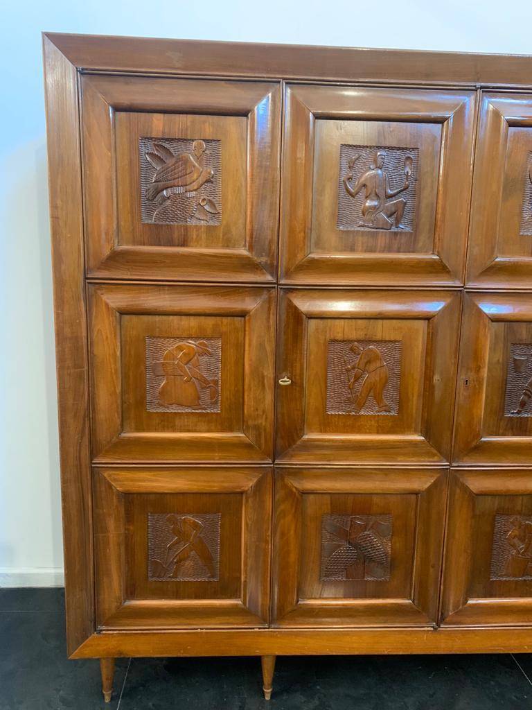 Closet cabinet of great quality solid walnut, has 5 door panels carved with characters of futuristic taste with gouged bottom, all resting on conical feet with brass ferrules. Under the base mold of the company illegible. The lines are typical of