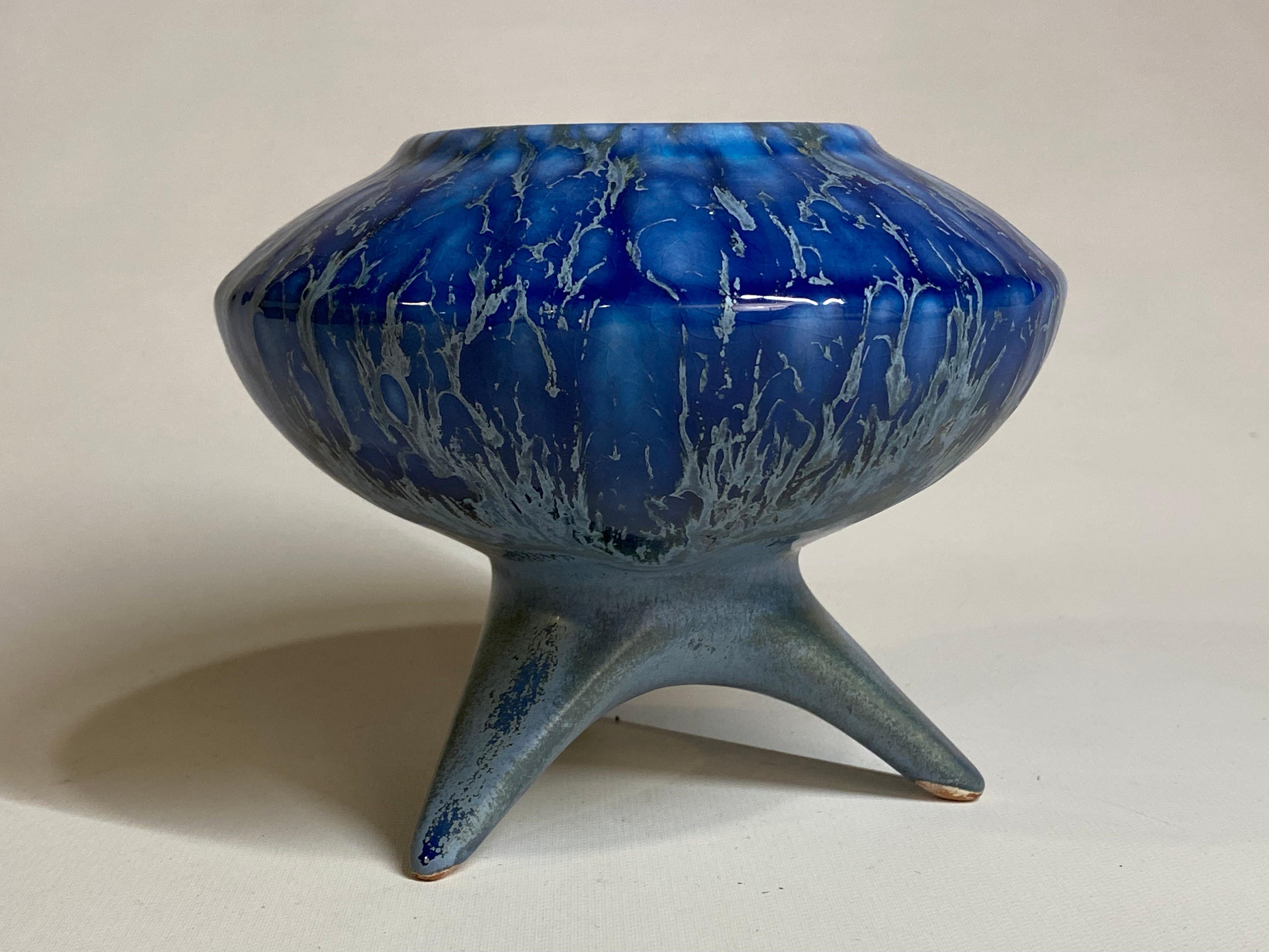 Amazing futuristic Mid-Century Modern fat lava and flambe blue glazed tripod vase, circa 1950-1960. Glossy to mat drip glazed vessel with three splayed legs holding up a space saucer type bowl. The glaze colors range from a deep gloss blue to a