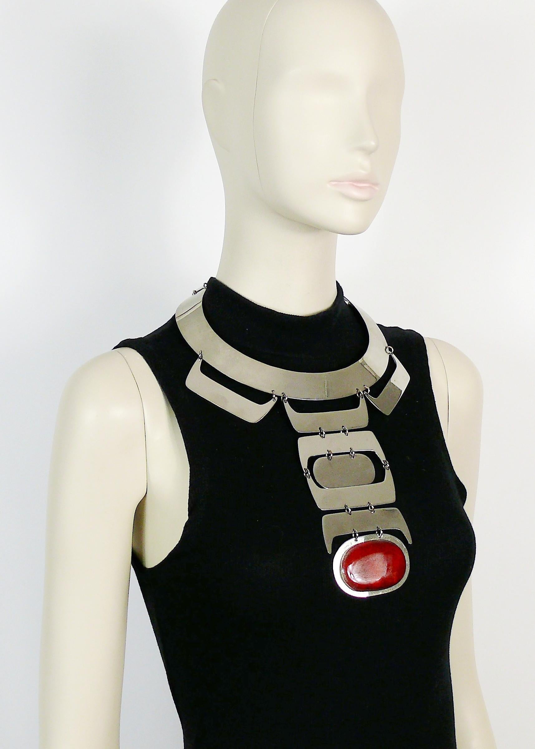 Futuristic Space Age vintage silver toned plastron choker necklace featuring a large oval red ceramic cabochon pendant.

Hook clasp closure.

Unsigned piece.
Stickers with references - runway piece ? prototype ?

JEWELRY CONDITION CHART
- New or