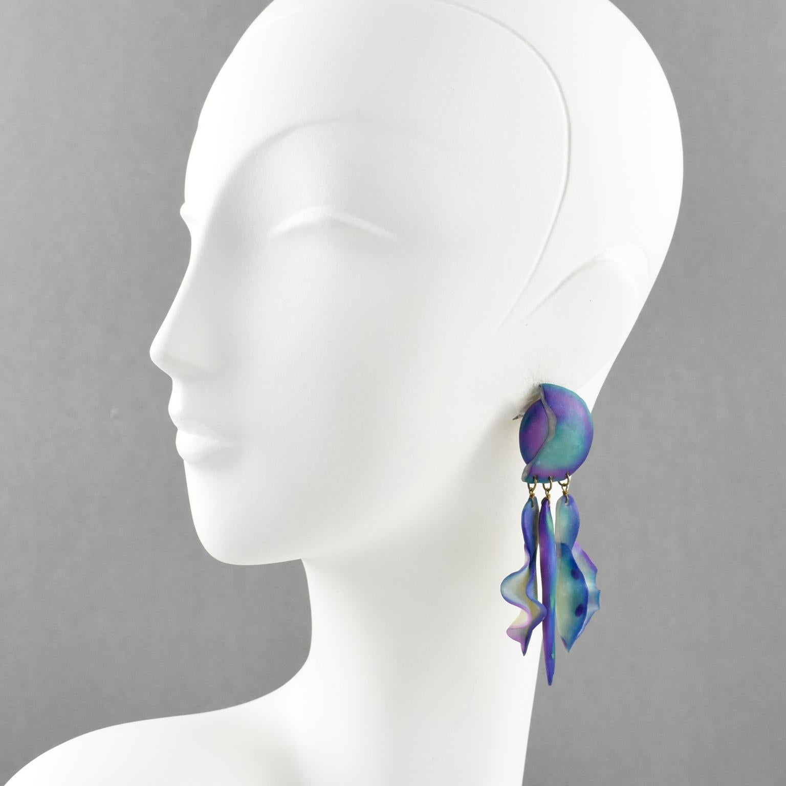 Stunning extra-long Resin pierced earrings. They feature futuristic dangling drop designs with carved shapes and an organic feel. Assorted colors of blue, turquoise, and purple with a shaded pattern. There is no visible maker's mark. They are made