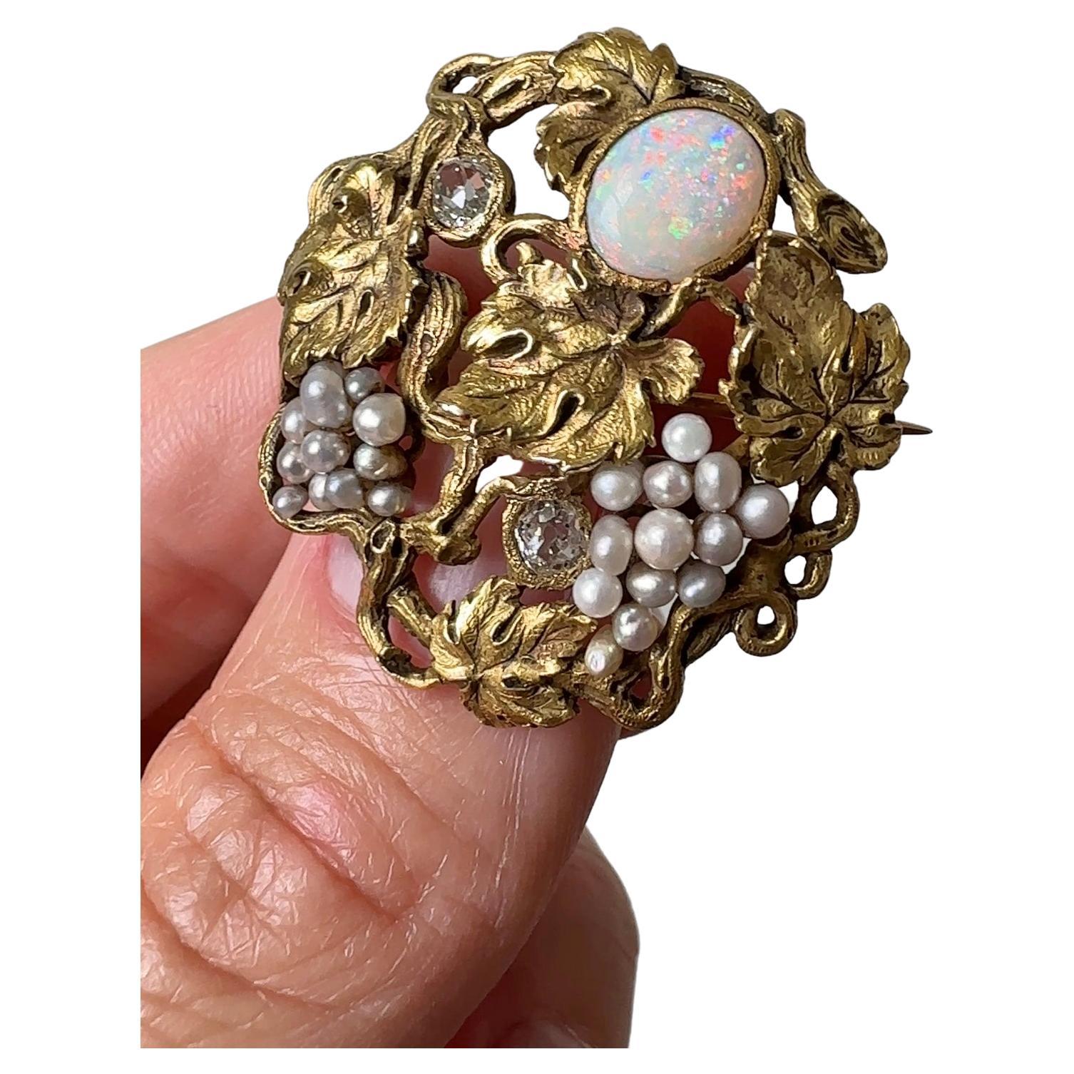This enchanting Arts & Crafts era brooch has been artfully designed and meticulously hand-crafted in 14 karat gold by F.W. Lawrence, circa 1900. An electric cabochon opal moon and two glittering old mine-cut diamond stars peek through luminous pearl