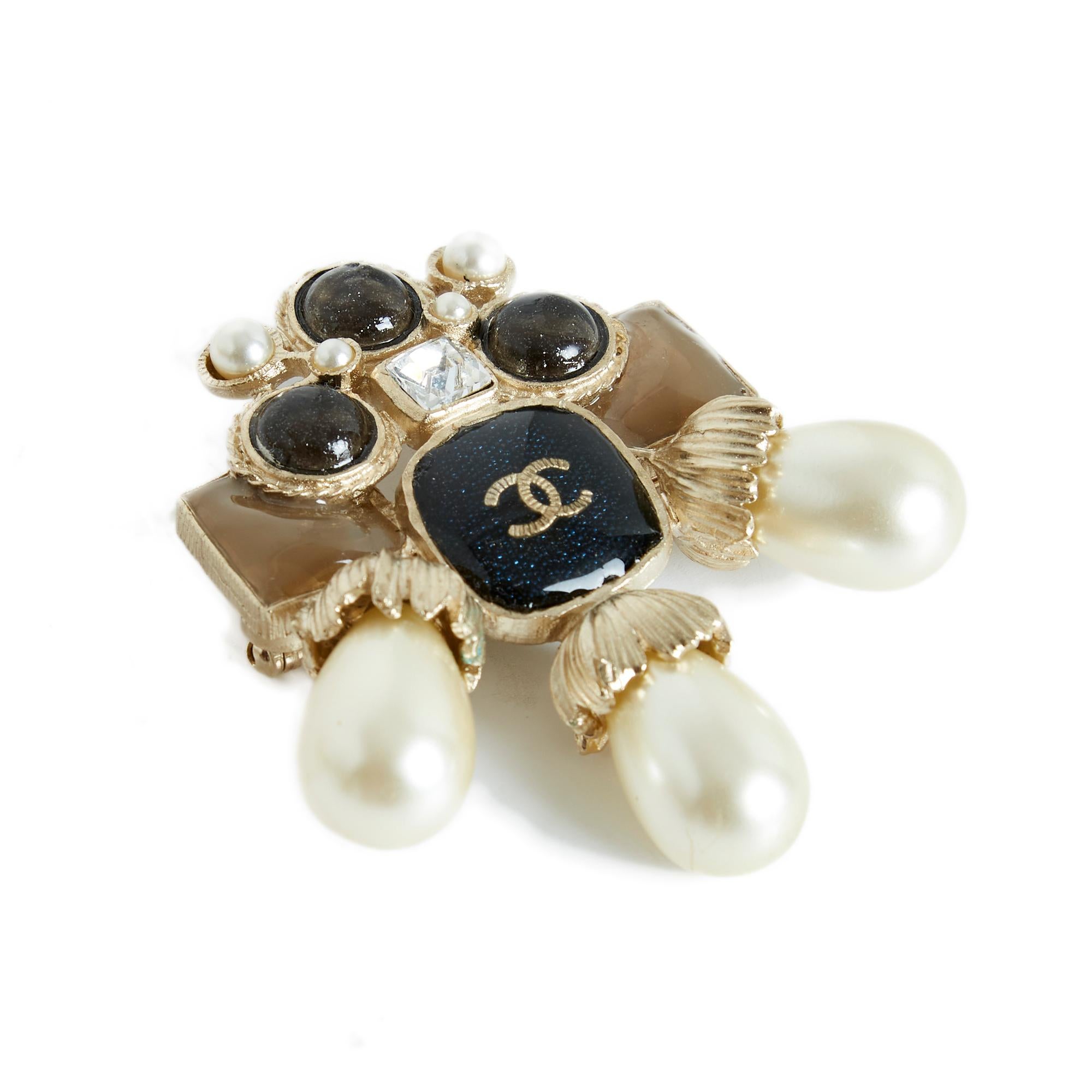 Chanel brooch AW2016 collection in lightly gilded metal (between gold and silver), XL format, central cabochon covered with slightly glittery black enamel and inlaid with a CC logo, cabochons of different shapes and slightly glittery colors, fancy
