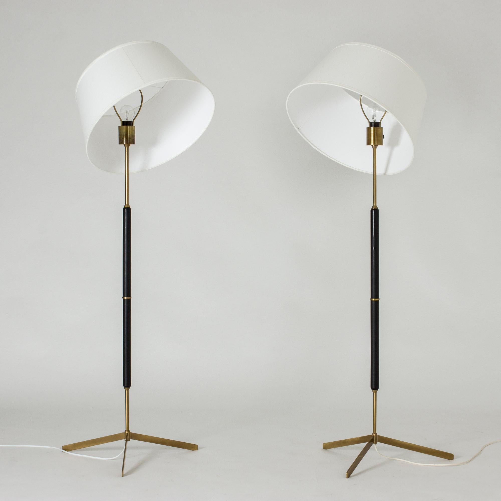 Very elegant pair of floor lamps by the Swedish publisher Bergboms with its tripod base, from the 1950s. The assembly of materials with the black wooden shaft, the structure and the brass ring gives it its original and modernist aesthetic.
