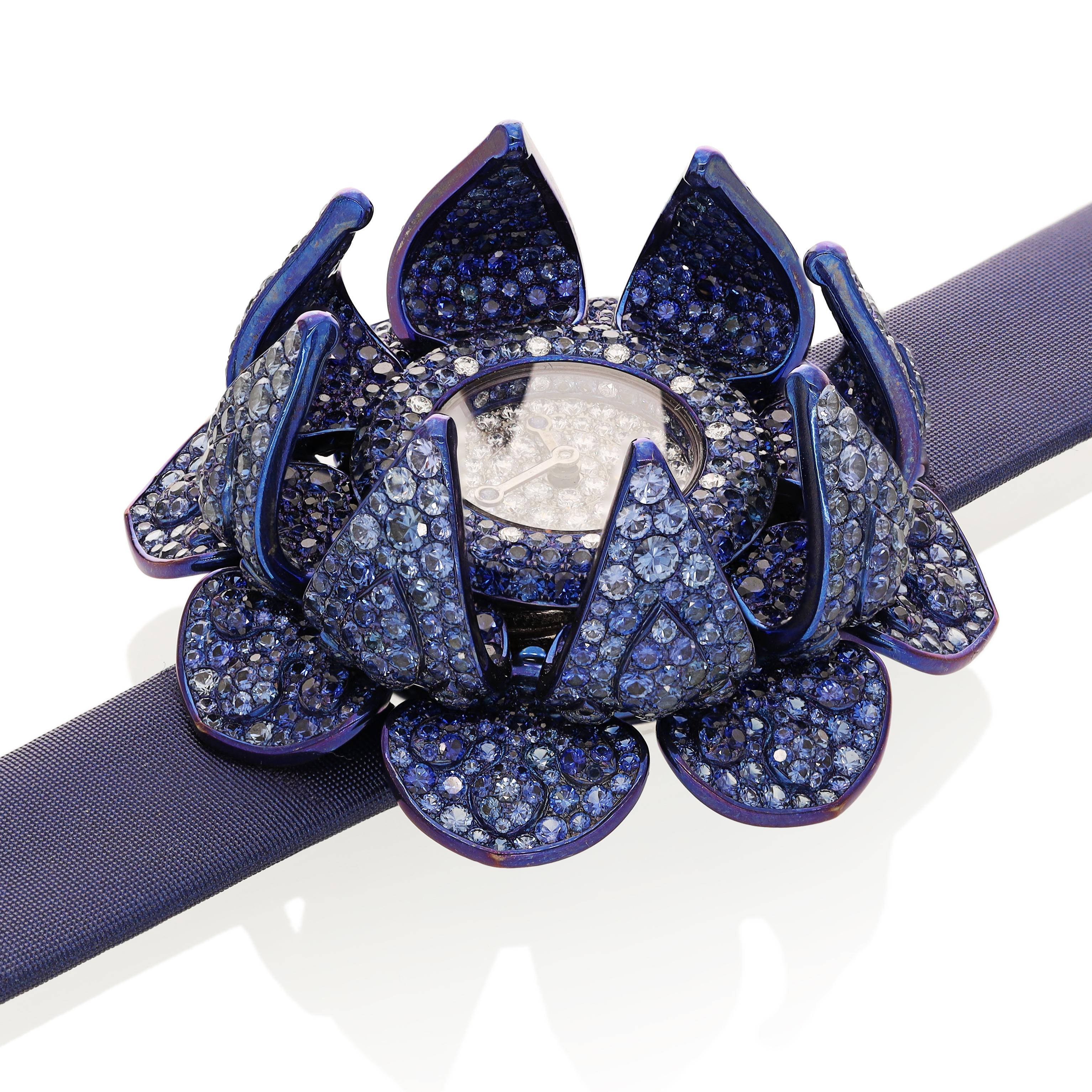 Der exquisite Zeitmesser ist ein Meisterwerk des Luxusdesigns mit einem einzigartigen floralen Motiv. Die Uhr ist mit einer Reihe von blauen Saphiren geschmückt, die sorgfältig gefasst sind und einen faszinierenden, schimmernden Effekt erzeugen. Die