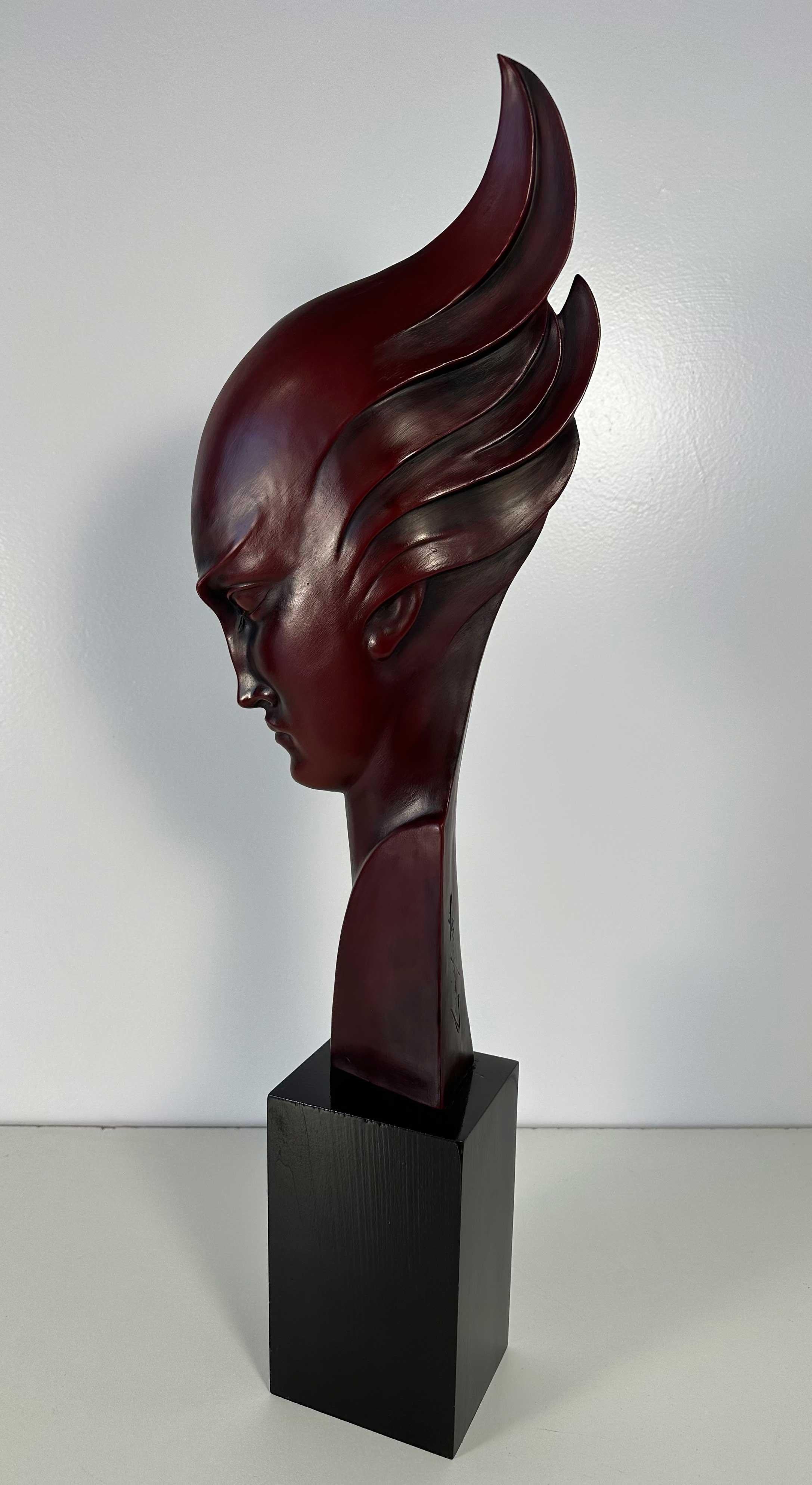 This Art Deco sculpture was produced in Italy and more precisely in Milan, by Guido Cacciapuoti in the 1930s. 

The base is in ebonized wood and the sculpture, a typical Art Deco stylized woman profile face, is in in red porcelain stoneware.

On the