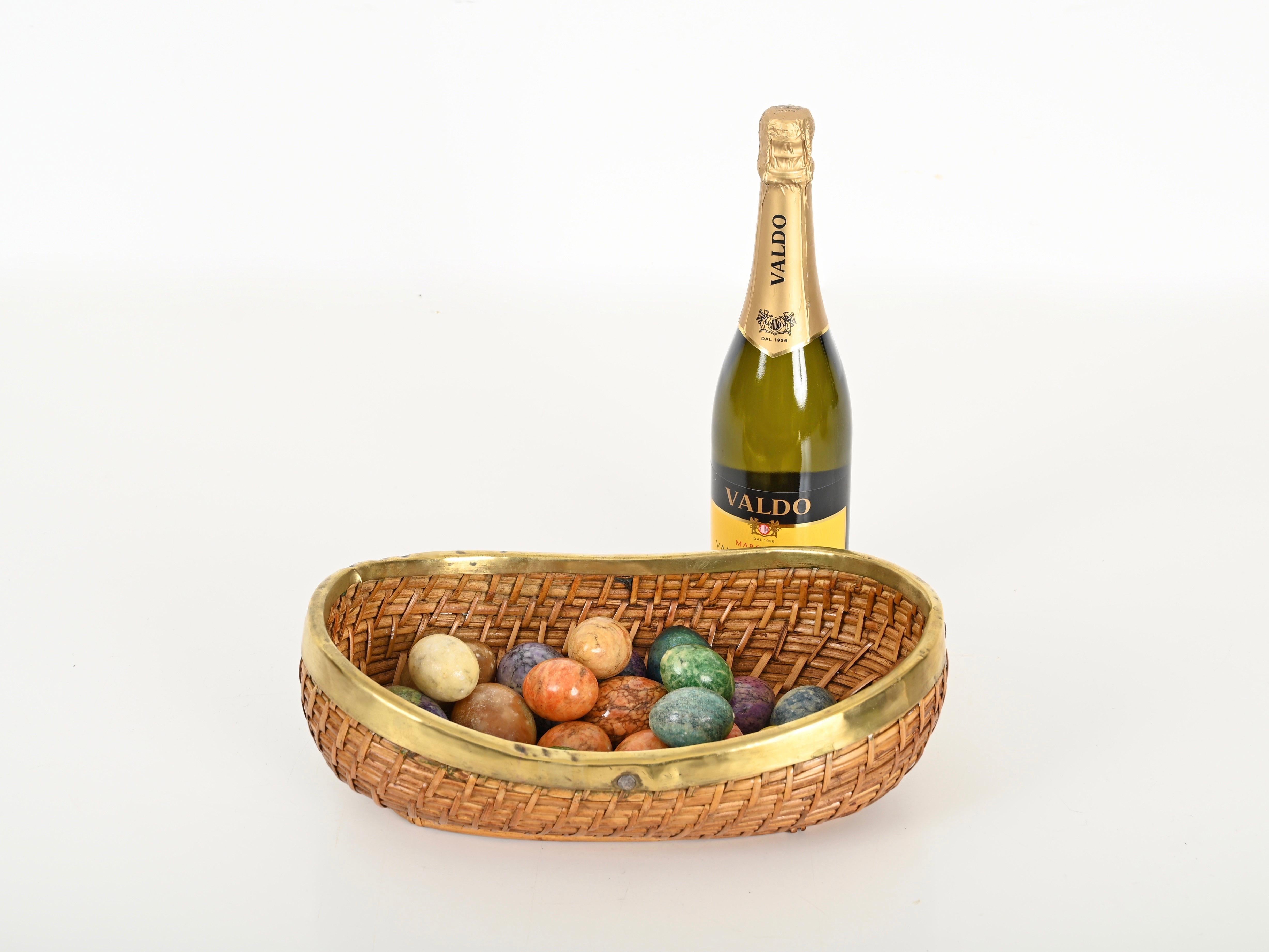 Splendida ciotola decorativa o vide-poche di grandi dimensioni della metà del secolo scorso, completamente realizzata in vimini di rattan intrecciato e ottone. Questa elegante ciotola in stile Costa Azzurra è stata disegnata in Italia negli anni
