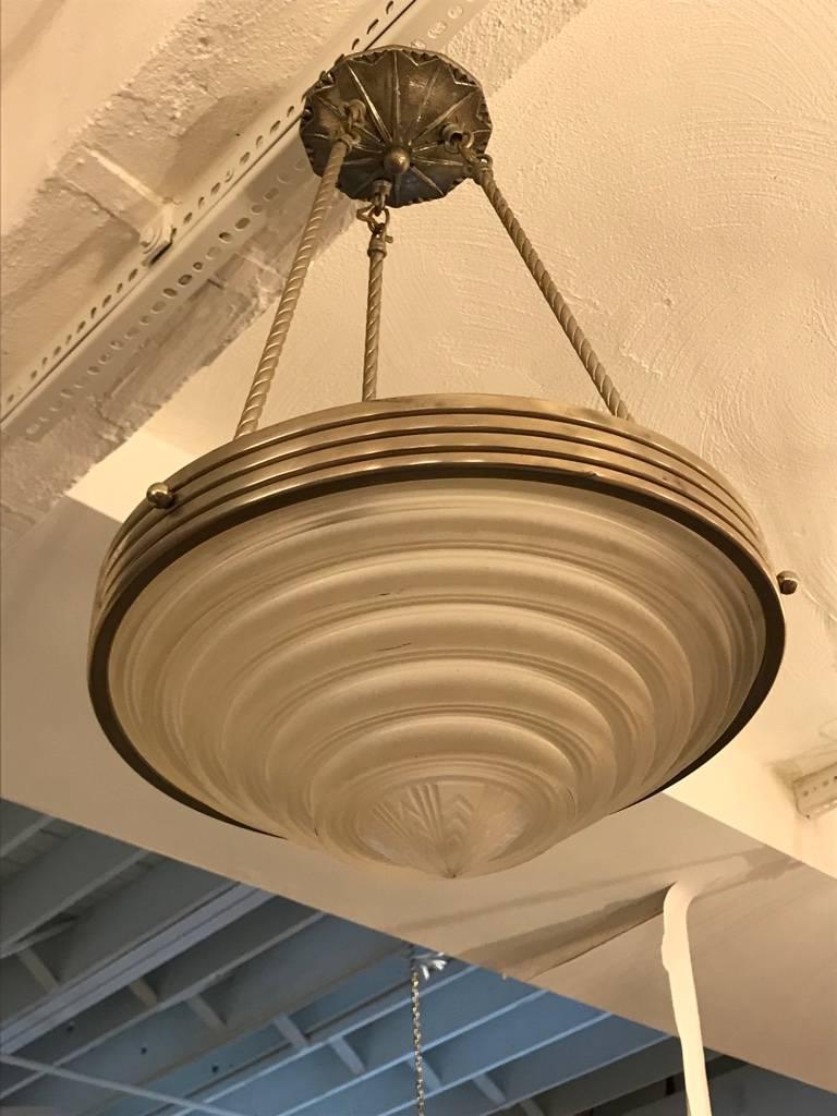 French Art Deco chandelier signed by Georges Leleu. With a beautiful center bowl in clear frosted glass with ribbed and geometric motif. Polished details on a nickel frame. Having three rods and ceiling cap. Has been rewired for american use. Having