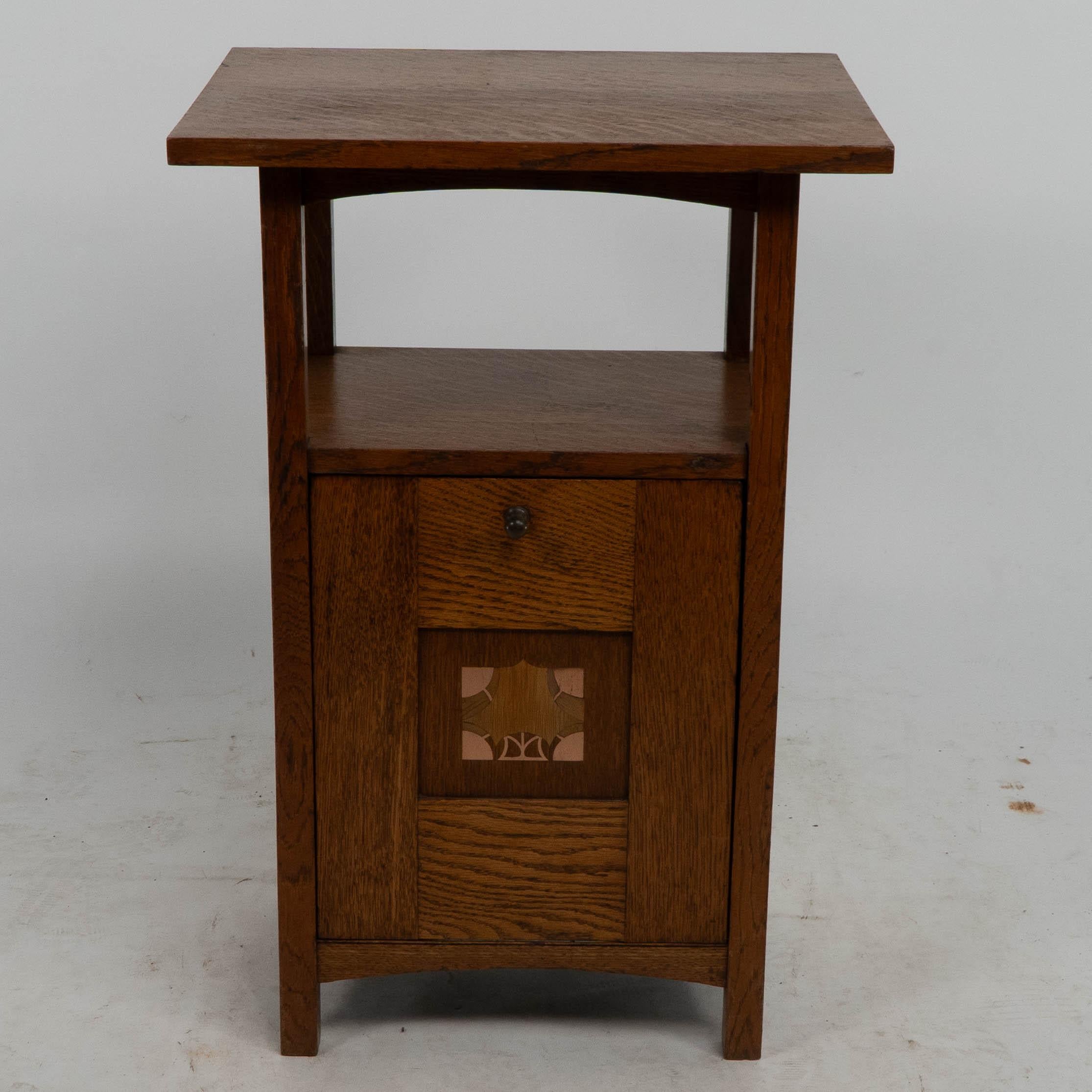 George Montague Ellwood. 
A rare Arts and Crafts oak purdonium made by J S Henry. 
A set of chairs also designed by G M Ellwood with similar inlays were exhibited at The Dublin Museum Exhibition held in 1905.