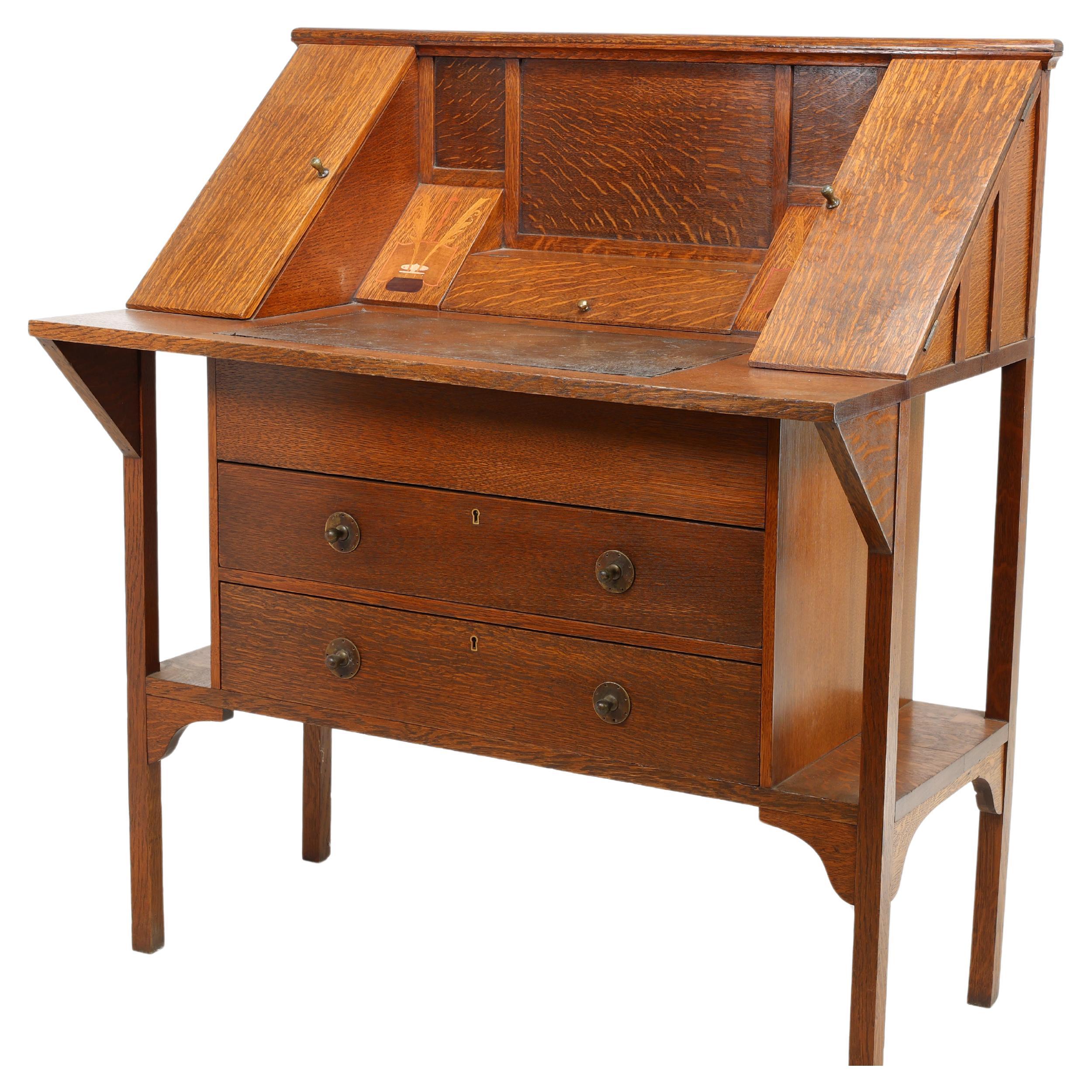 George Montague Ellwood (1875-1955) for J.S. Henry
An oak writing desk with sloping pen compartment just above the writing area flanked by stylised inlaid details of a pair of quills in ink pots the inlays of fruitwoods and copper, with fold out