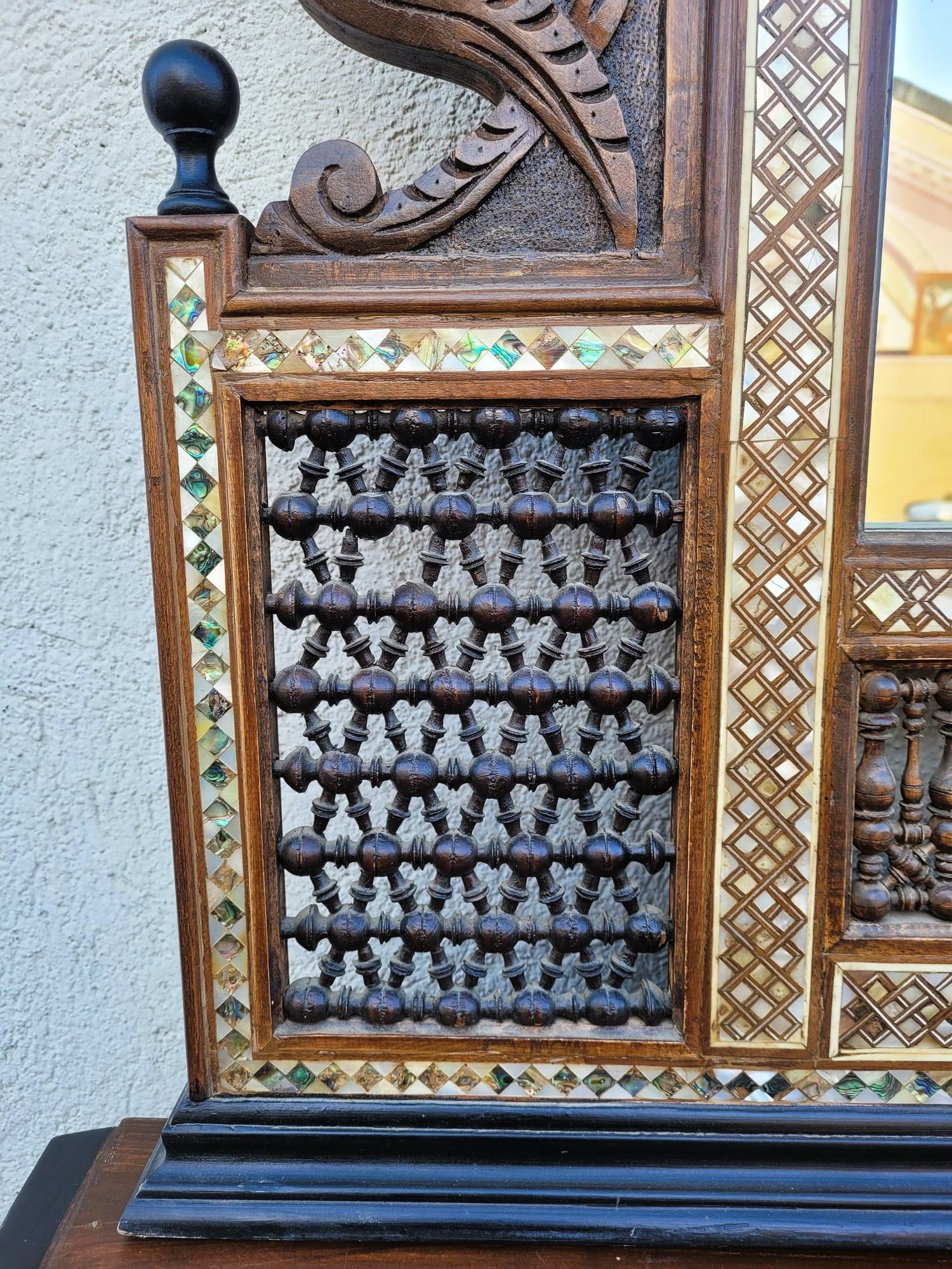 Large console topped with a mirror in the oriental style, with carved wooden decoration, geometric marquetry of wood, mother-of-pearl and bone, mashrabiya, Moorish arches, cartouche with inscription in Arabic

This console is typical of the work of