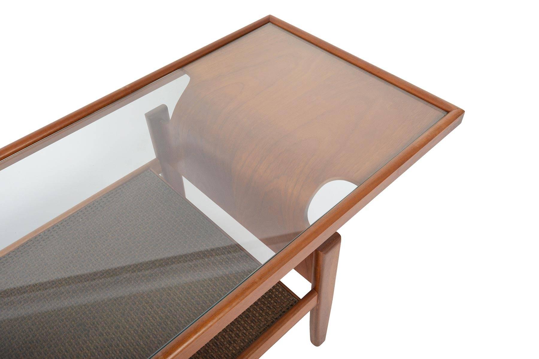 Cette table basse anglaise moderne du milieu du siècle par G Plan est une trouvaille rare. Fabriquées en teck, deux belles arches en bois courbé soutiennent un cadre en verre. Une étagère en bois surmontée de cannes se trouve à la base et offre un