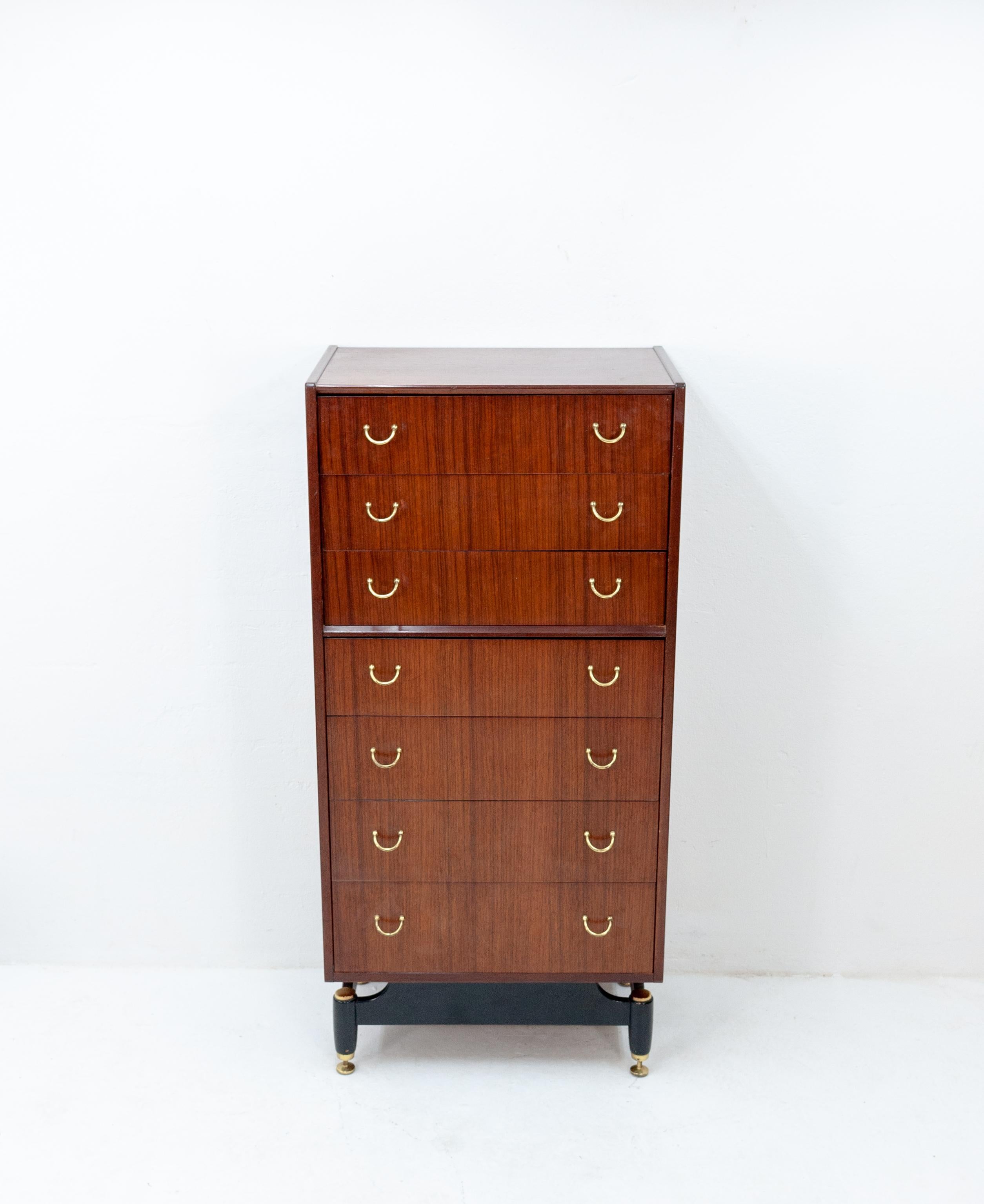 This is a beautiful tall chest of seven drawers with curved brass handles made by E. Gomme as an early G plan piece in the 1950s-1960s. Using tola wood (African mahogany) for the cabinet with an ebonized frame and legs with brass feet.
 