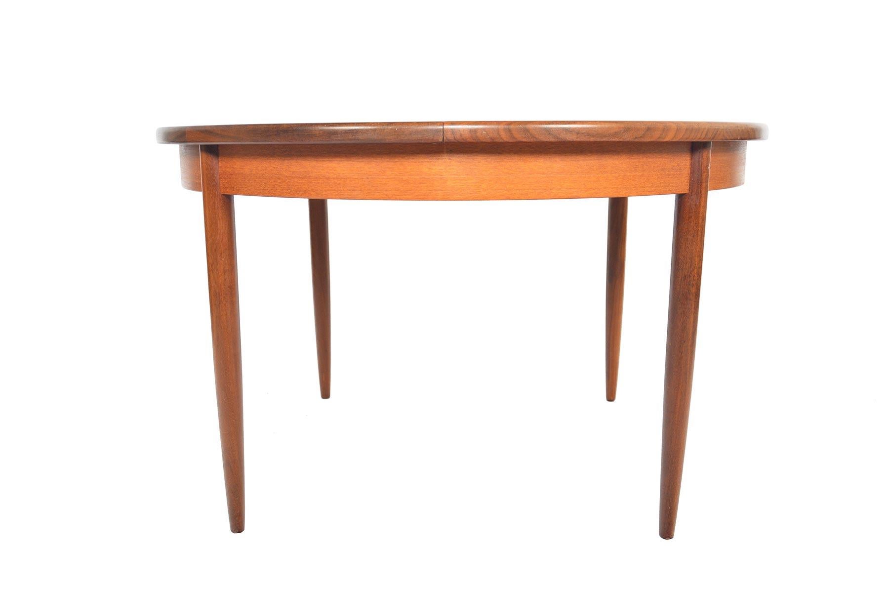 This beautifully simple round dining table was designed by Victor Wilkins for G Plan in the 1960s. The slab is banded in rich, contrasting afrormosia wood. Table expands to hold a collapsable butterfly leaf stored within the table. This table can