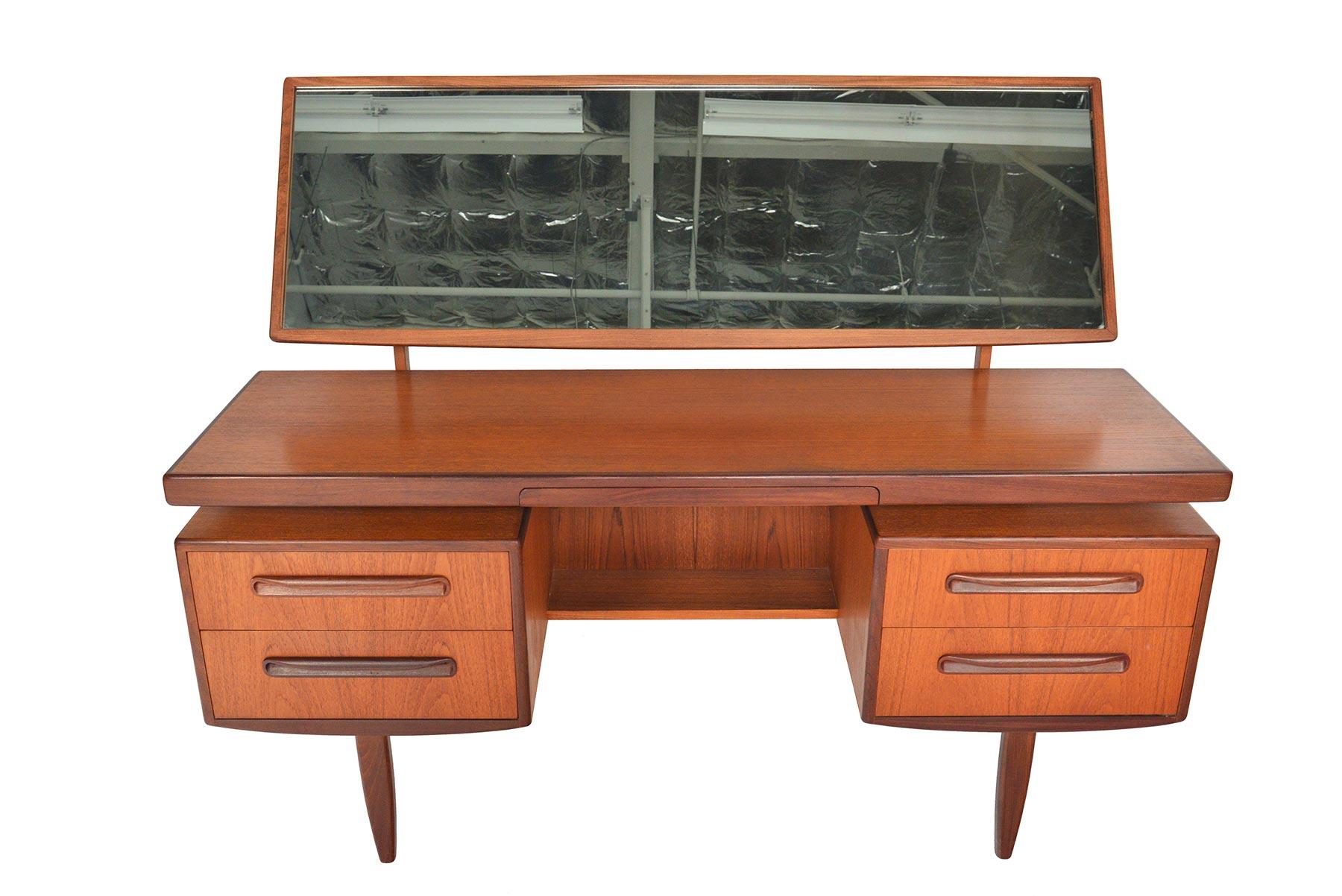 This English Mid-Century Modern G Plan Fresco floating top teak vanity desk was designed by Victor Wilkins in the 1960s. Mirror articulates and easily detaches for storage. Middle drawer pulls out to reveal a deep, velvet lined jewelry drawer. Two