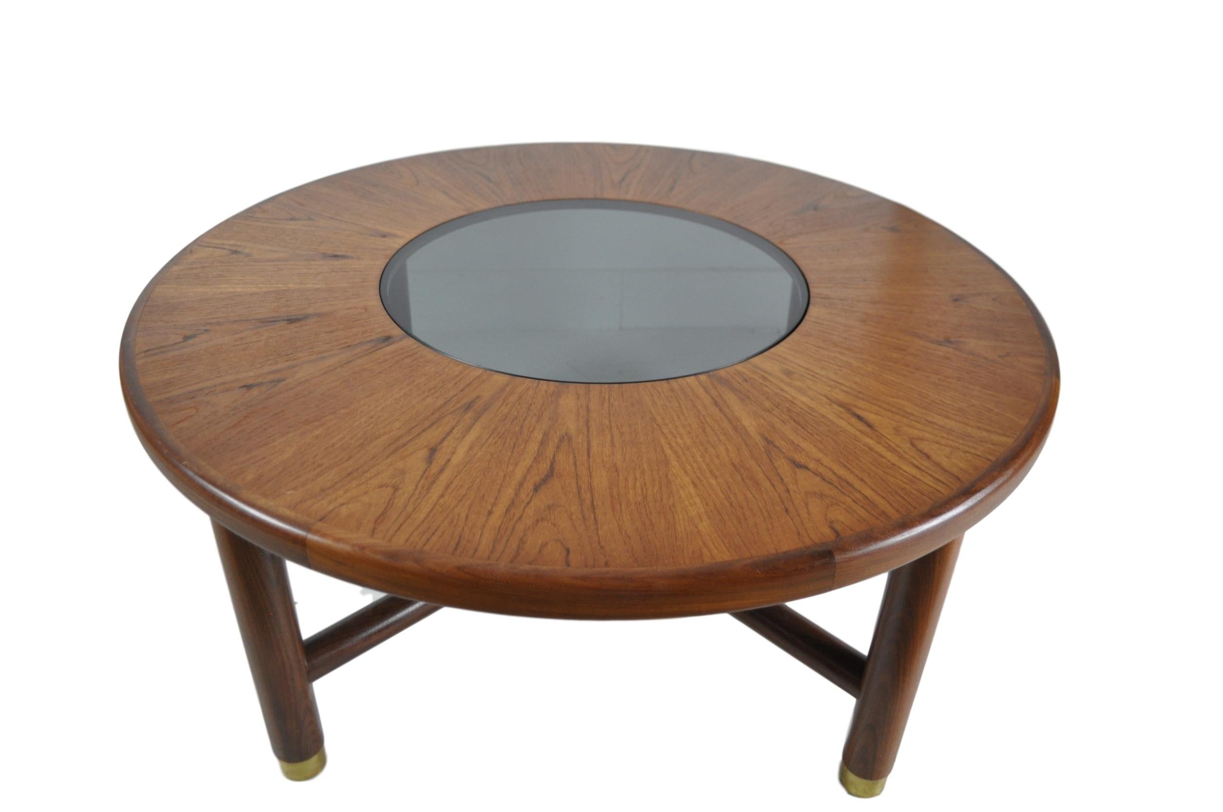 Rare round teak and smoked glass coffee table by G-Plan, circa 1960. This particular table is of the darker teak variant and some minimal wear around the brass plate leg detailing.