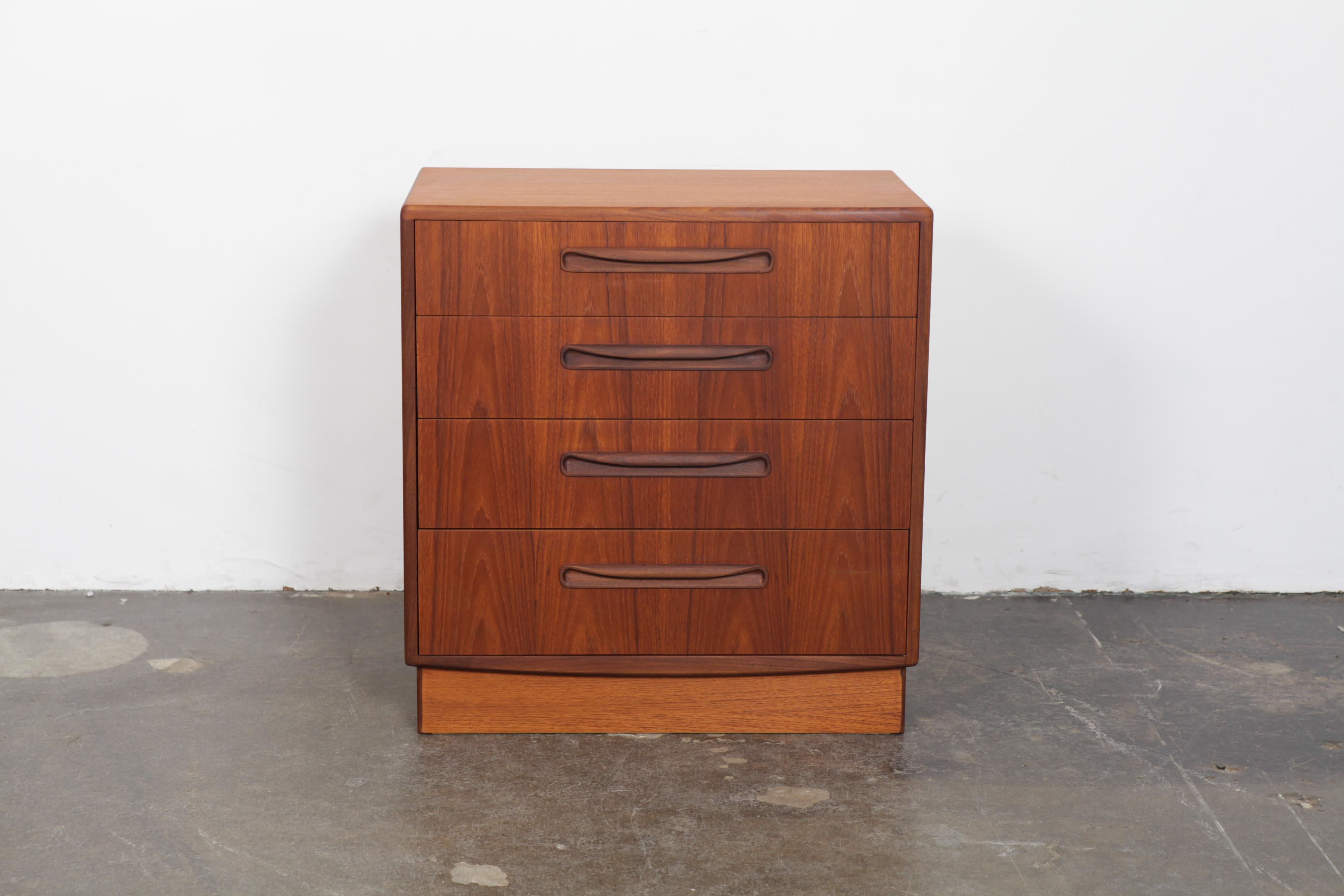 Newly refinished G Plan four-drawer teak and afromosia wood smaller dresser on a plinth base, 1960s, part of the 'Fresco' line, England. Two toned with Classic curving carved handles on a plinth base, designed by VB Wilkins.