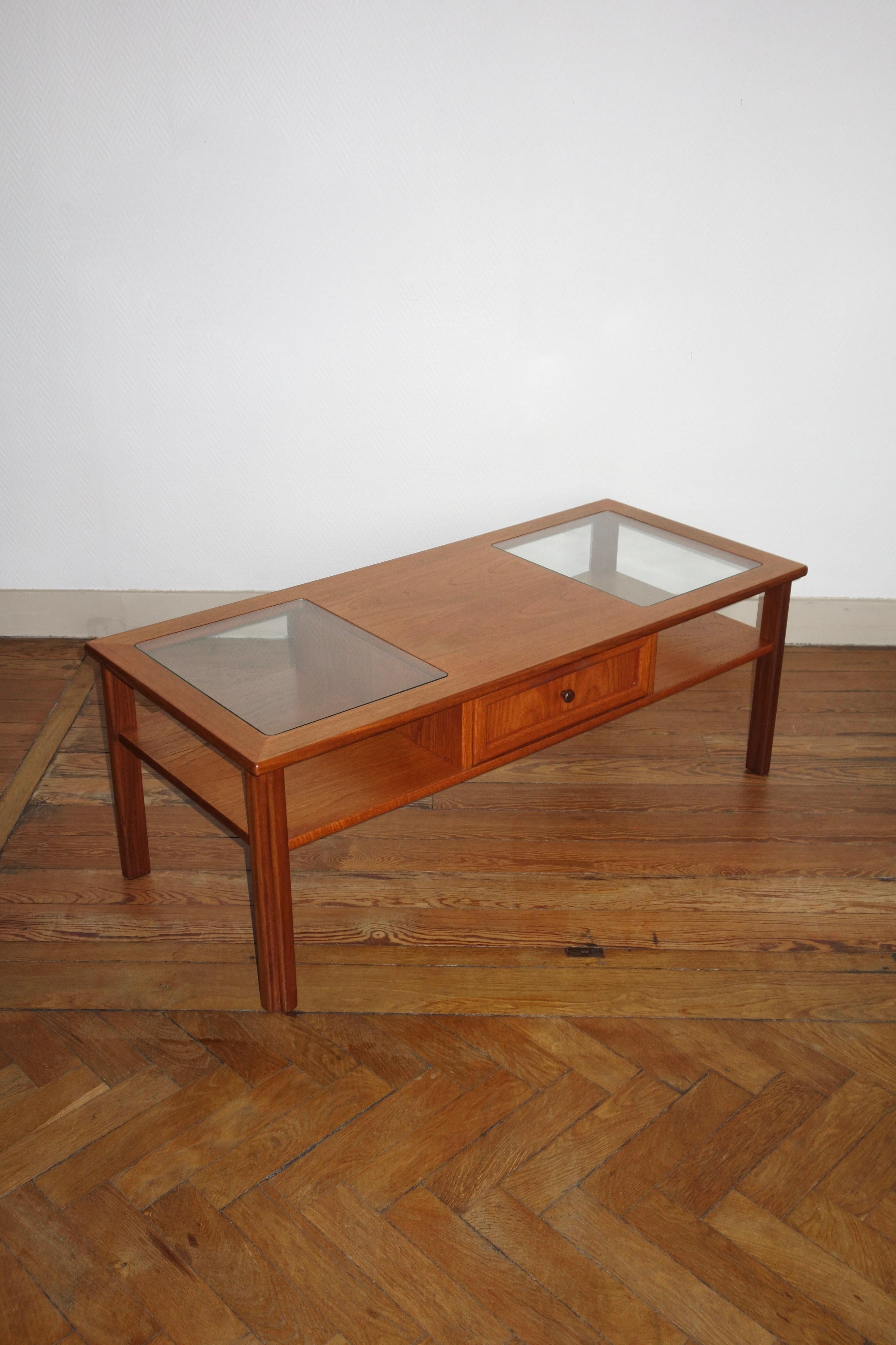 Vintage coffee table created by Gplan, manufactured in the United Kingdom, 1970s. Rectangular shape, teak with 2 glass trays. Beautiful storage capacity, through drawer with solid teak knobs and niches on each side. Publisher's label inside the