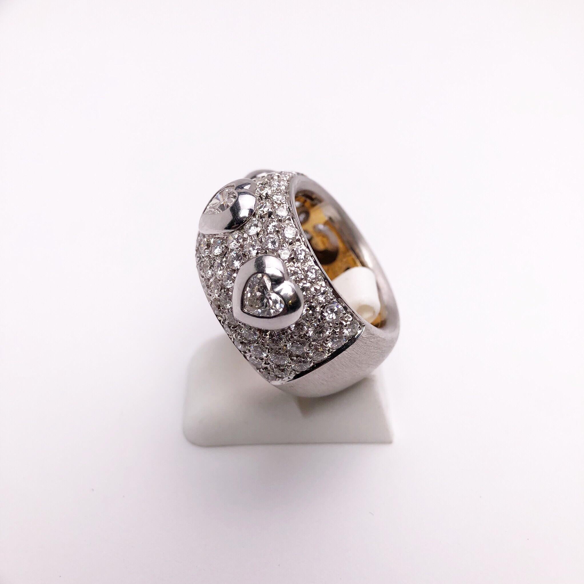 Made exclusively for Cellini by  g.Verdi of Italy. This wide band ring is pave diamond set,along with three bezel set heart shaped diamond solitaires. Total diamond weight 3.39 carats. The pave diamonds go halfway around. The other half is composed