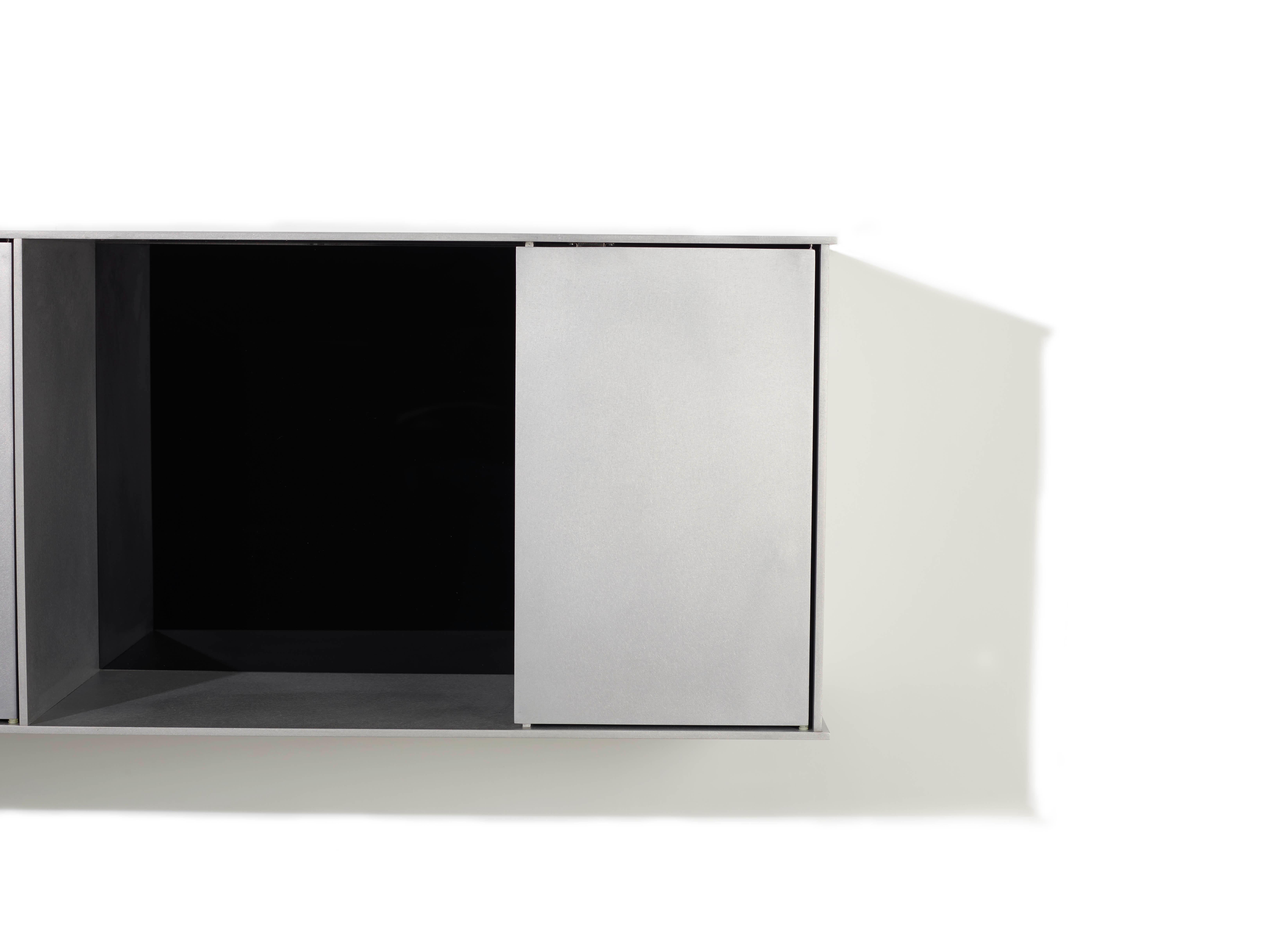 The Minimalist wall-mounted G shelf is sculpted out of 1/4 inch thick, wax-polished aluminum with two Minimalist pin-hinged doors. Each shelf has an inset welded U-channel that spans the length of the shelf and easily mounts on included custom-bent