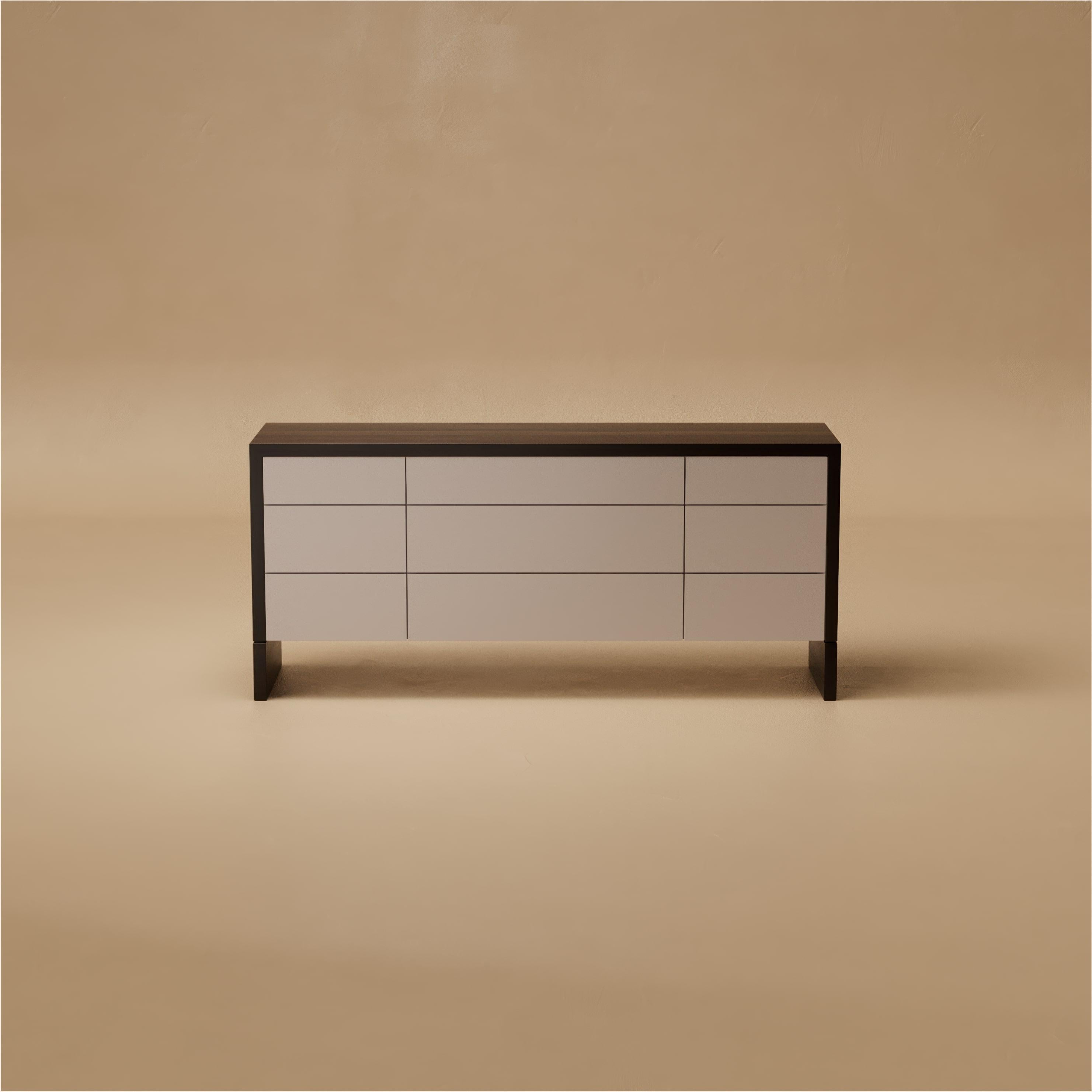 Il comò Grant è minimale nelle forme ma ricco di raffinatezza. Una struttura in noce circonda i cassetti laccati satinati, il cui design senza soluzione di continuità con apertura a pressione è accentuato da un intarsio in pelle sul piano superiore.