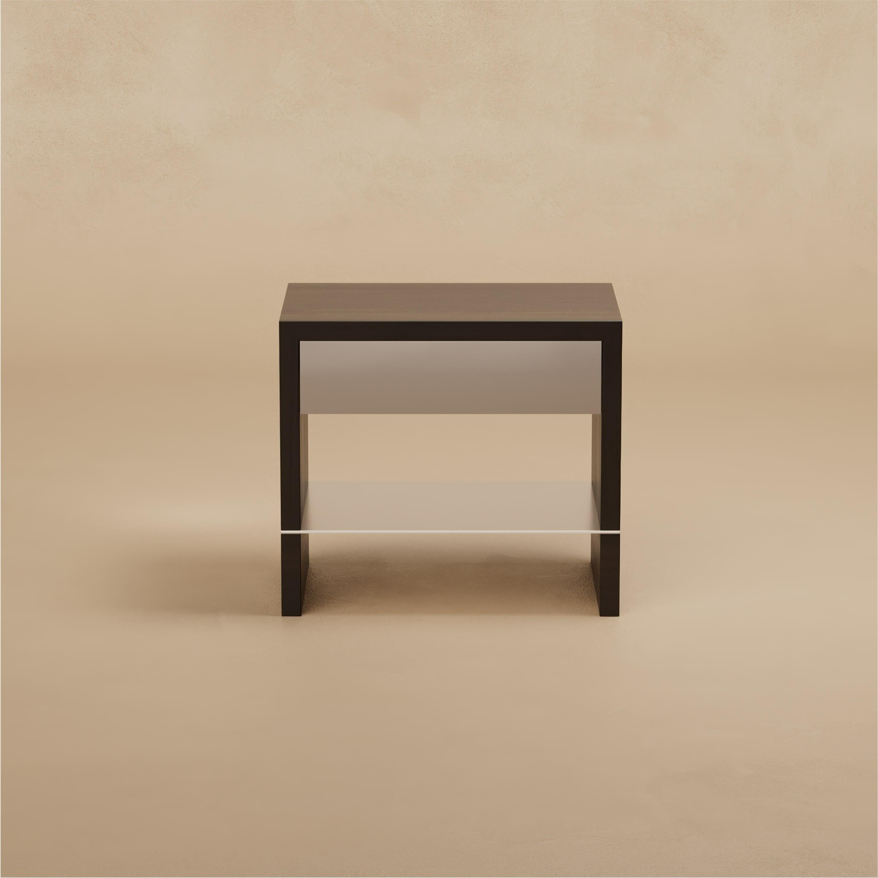 La table de chevet Grant réduit la chambre à coucher à l'essentiel. Des tiroirs en laque satinée, doublés de cuir, sont logés dans un cadre en noyer, tandis qu'une mince étagère en métal complète la composition. Le résultat est calme, équilibré et