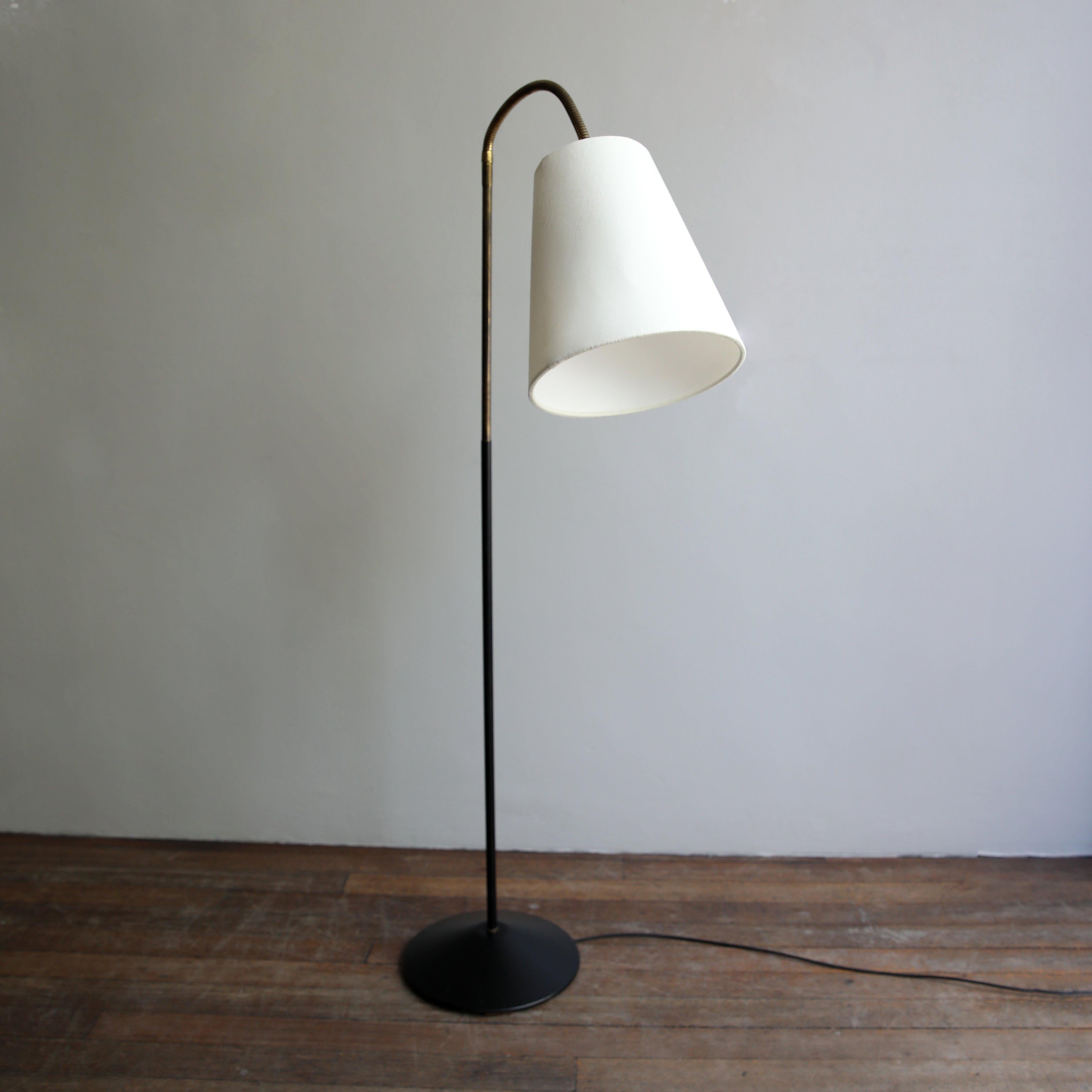 A floor lamp designed in the late-1950s by GA Scott for Maclamp, UK.
The lower half of the light’s stem and conical base are black lacquered aluminium.
Raising from the black stem is a short pole section of brass which leads into a brass gooseneck
