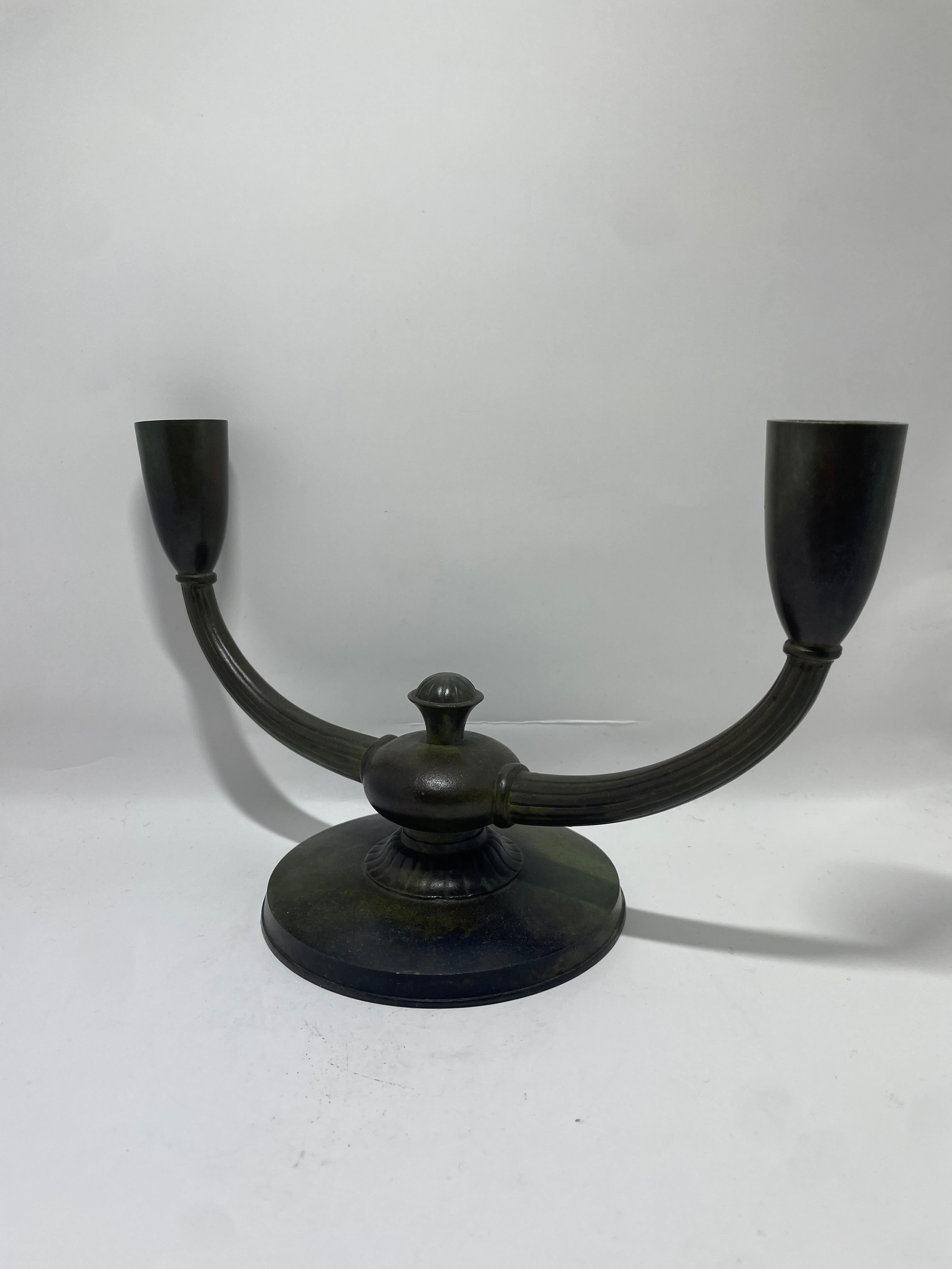 Un sorprendente candelabro in bronzo Art Déco realizzato dal rinomato produttore svedese GAB (Guldsmedsaktiebolaget), intorno agli anni Trenta. Questo elegante portacandele a due bracci presenta una ricca patina invecchiata e una forma