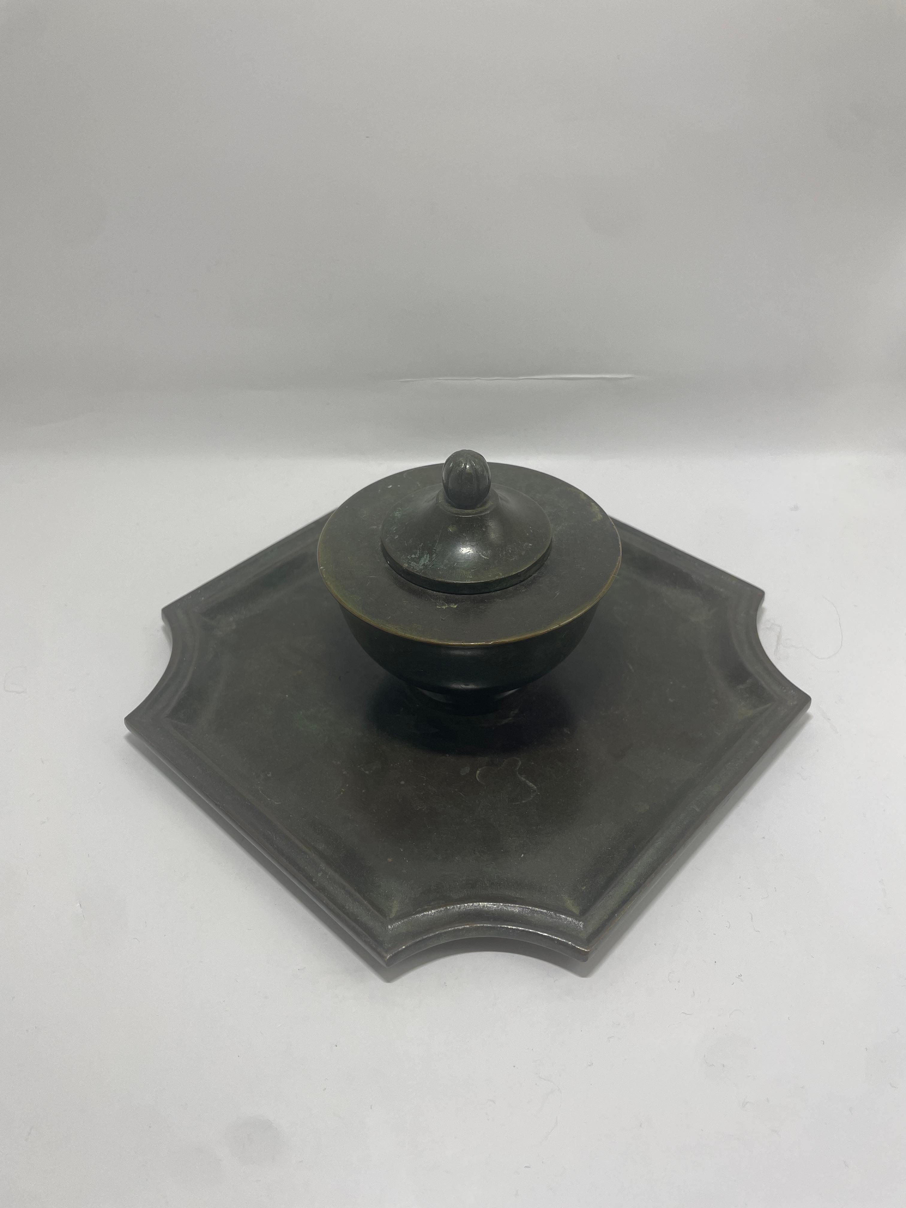 Elegante calamaio in bronzo prodotto da GAB (Guldsmedsaktiebolaget), Svezia, circa 1930. Questo calamaio di ottima fattura è caratterizzato da un vaso liscio e arrotondato con un coperchio scultoreo, appoggiato su un vassoio quadrato dai bordi