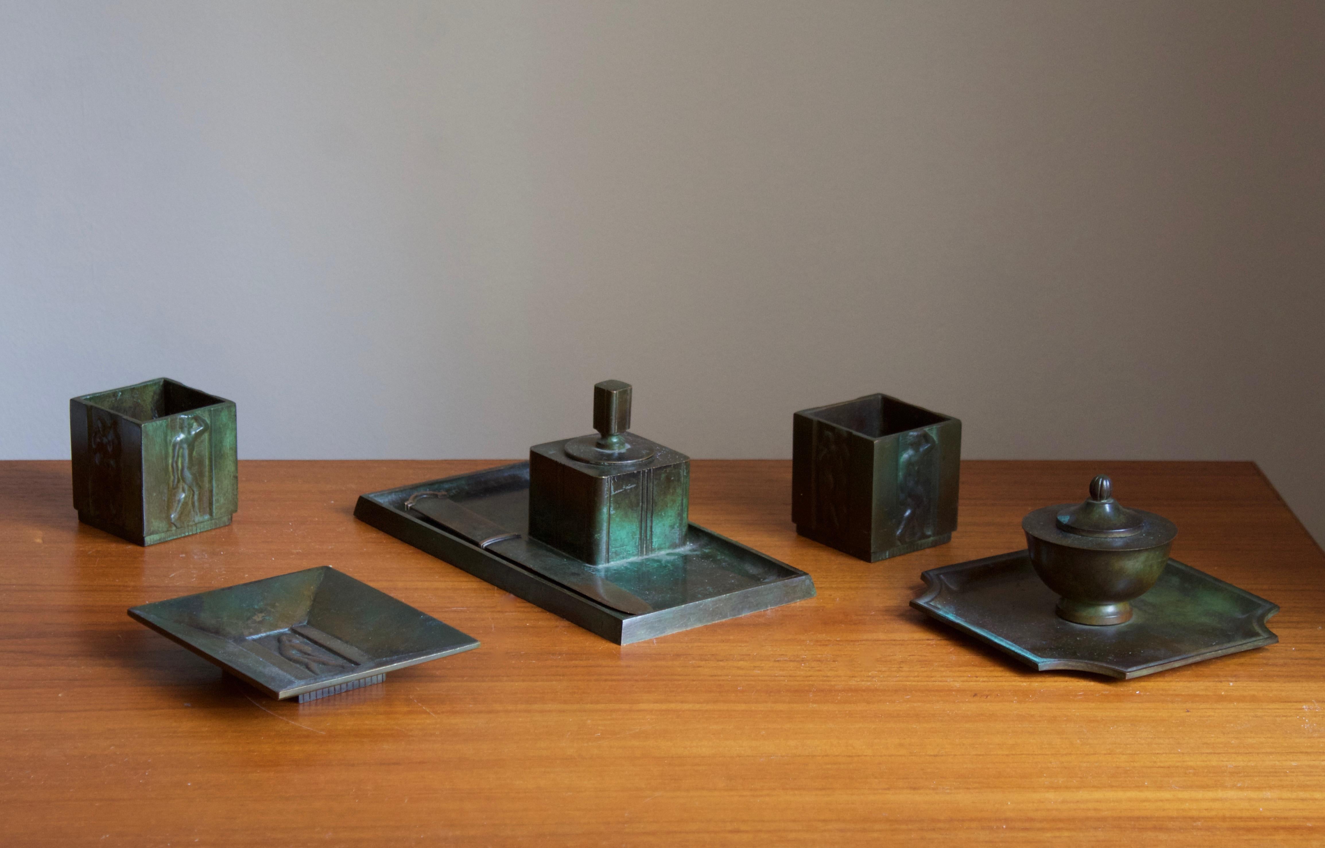 A set of desk accessories / desk set, including trays, inkwells, containers and a letter knife, designed and produced by GAB, stamped with makers marks, Sweden, 1930s. In cast bronze.

Stated dimensions are of the tray with built-in inkwell in the
