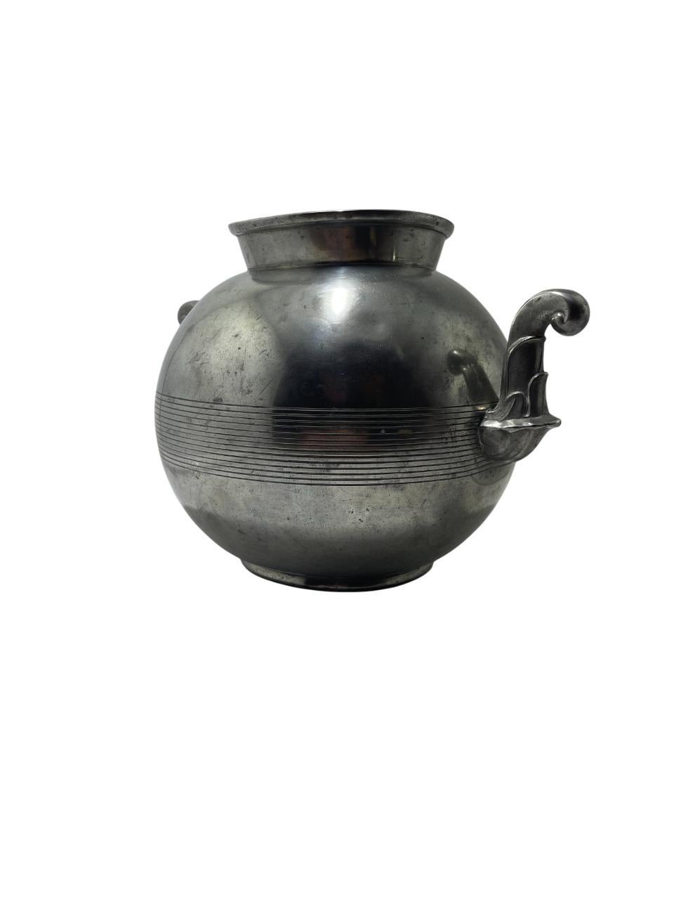 A striking Art Deco pewter vase by Guldsmedsaktiebolaget (GAB), Sweden, dated 1939. This sculptural piece features a bold, rounded body accented by elegant double scroll handles and a series of horizontal engraved lines that wrap around its