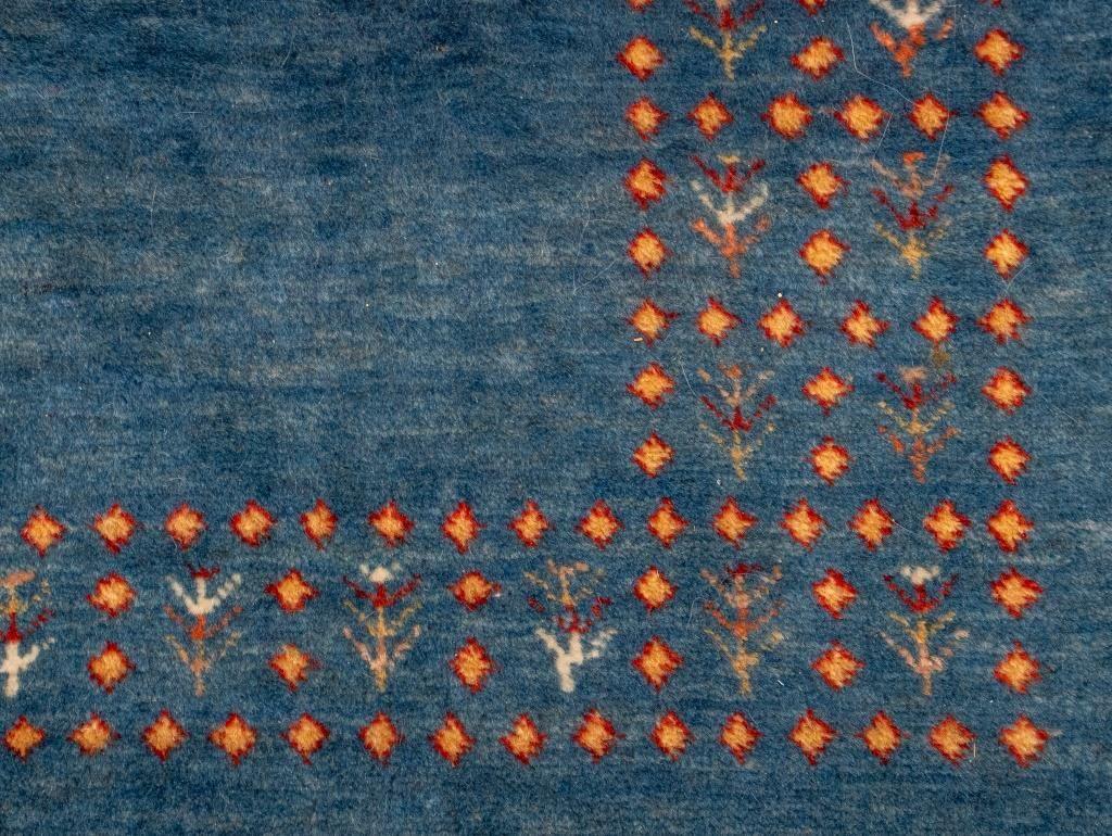 Tapis noué à la main en laine persane, à fond bleu abrash présentant un motif géométrique simple, avec une étiquette indiquant 