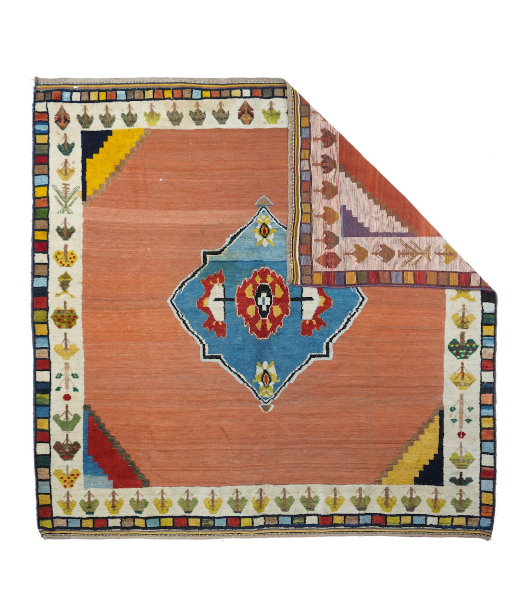 This Fars Province, SW Persian, rustic scatter shows an abrashed rust-red open field centred by a strongly abrashed light/cerulean blue octogramme enclosing a rosette and two primitive palmettes. Stepped corners in red, ecru, goldenrod and cerulean