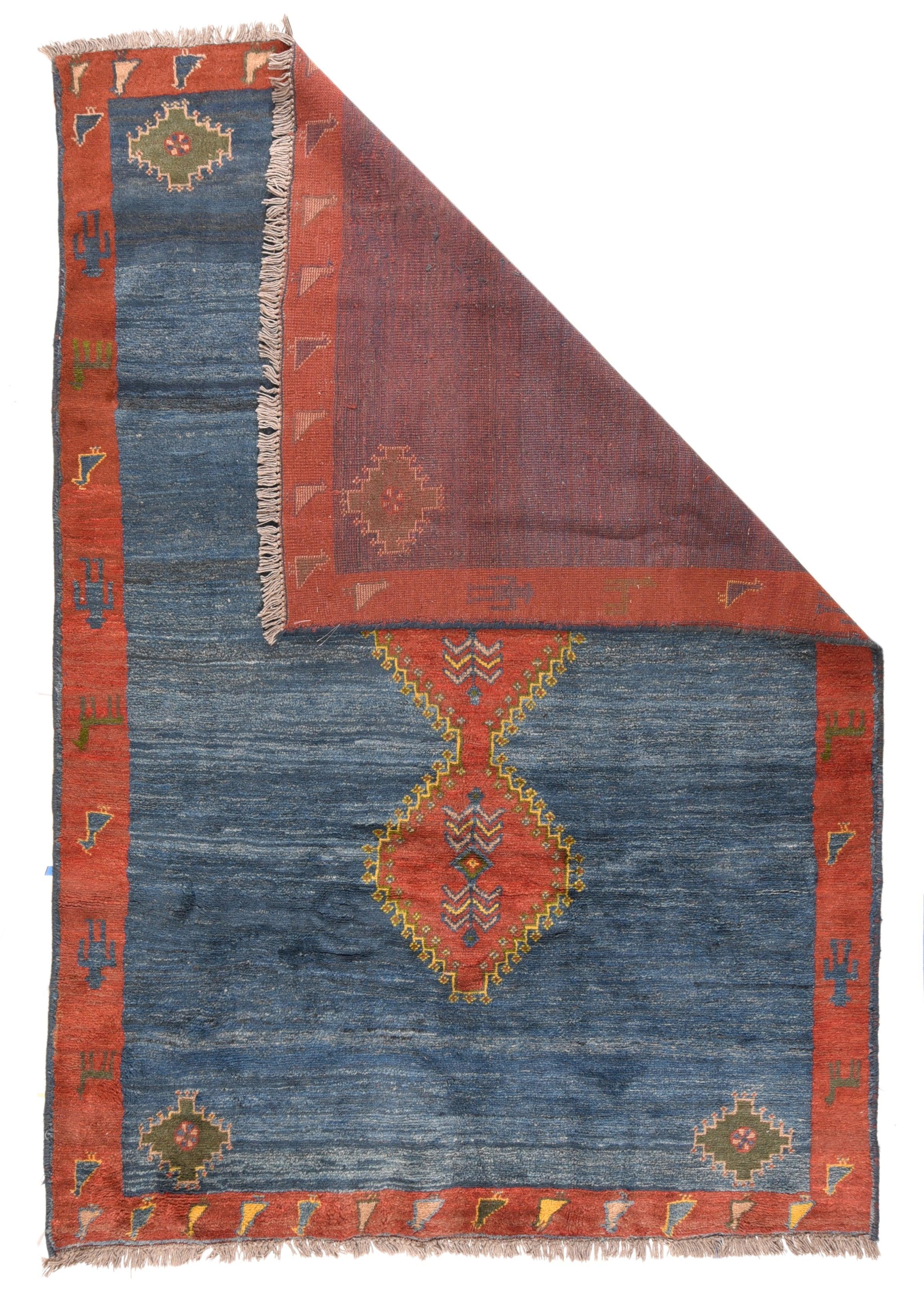 Gabbeh-Teppich 6'8'' x 9'9''. Dieses Tribal-Stück zeigt ein wunderschön abgewetztes, jeansblaues, offenes Feld, in dessen Mitte ein rotes, dreiteiliges Stabmedaillon aus roten Sechsecken mit gelben Hakenfransen steht. Kleineres Zimmer mit roten