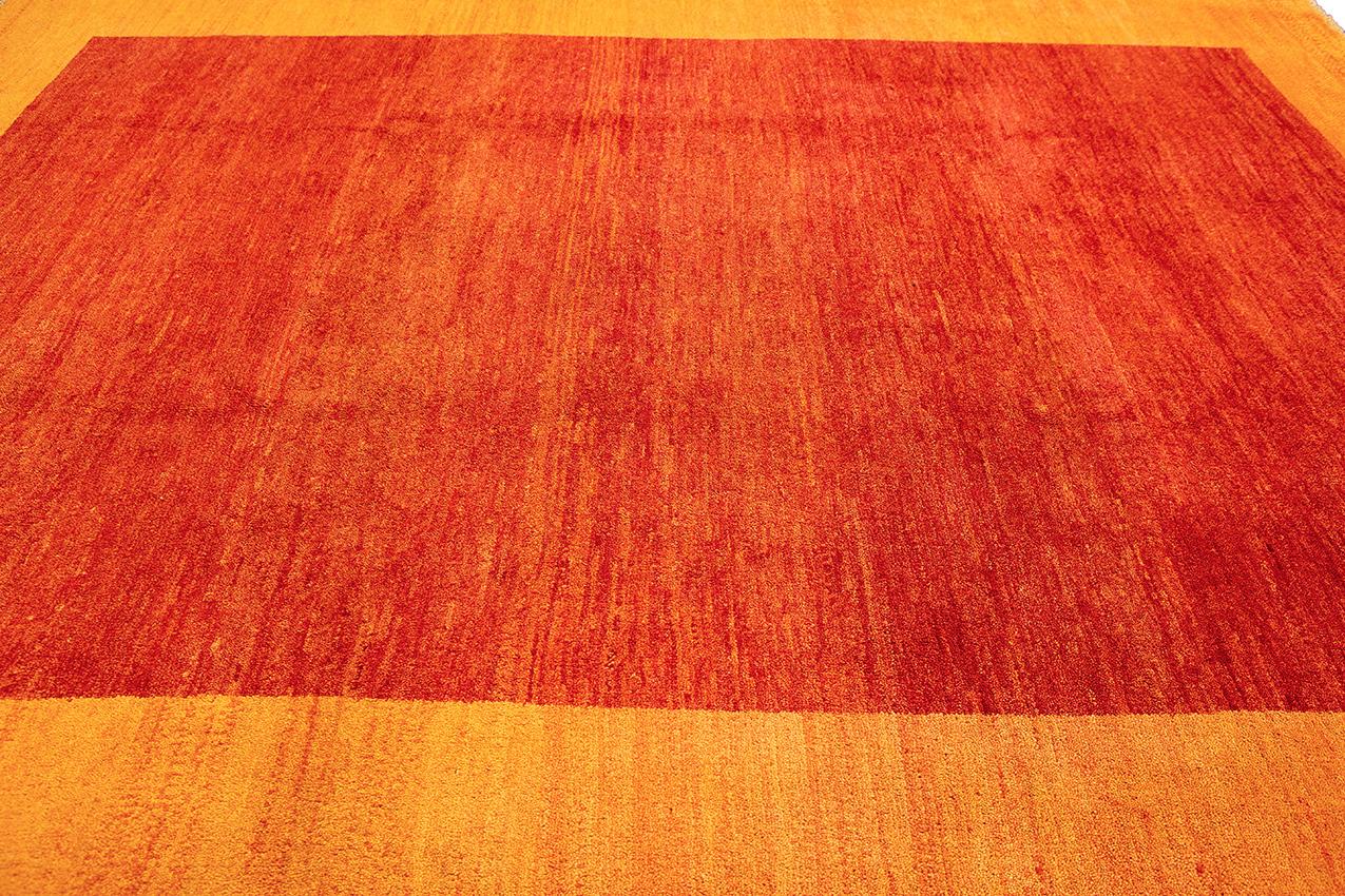 Il s'agit d'un tapis Gabbeh spécial - une fusion captivante de style contemporain et d'artisanat traditionnel. Ce tapis exquis présente un champ rouge frappant avec une bordure orange, créant une pièce centrale vibrante et visuellement attrayante