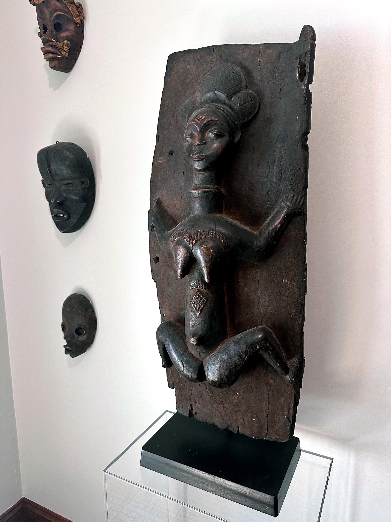 A wonderful Punu wooden door panel (one of the original pair) with the iconic carved female figure circa mid-20th century. These door panels were used for granary in Gabon. The door features an idealized female figure with three-part coiffure and