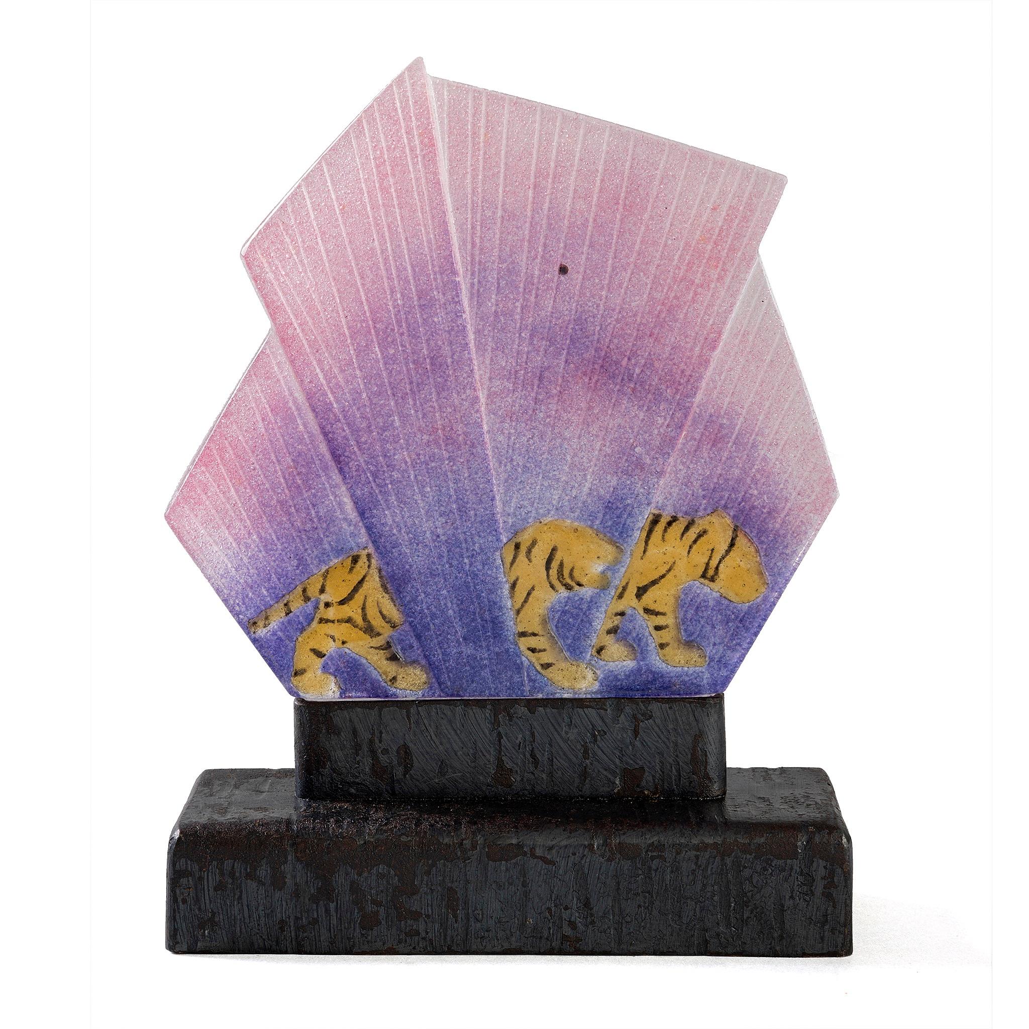 Lampe à Pate-de-verre de Gabriel ROUSSEAU, représentant deux tigres rouges traquant leur proie dans un éventail d'herbes violettes. Le pate-de-verre repose sur une base en fer forgé également incisée de rainures en forme de tigre. La population