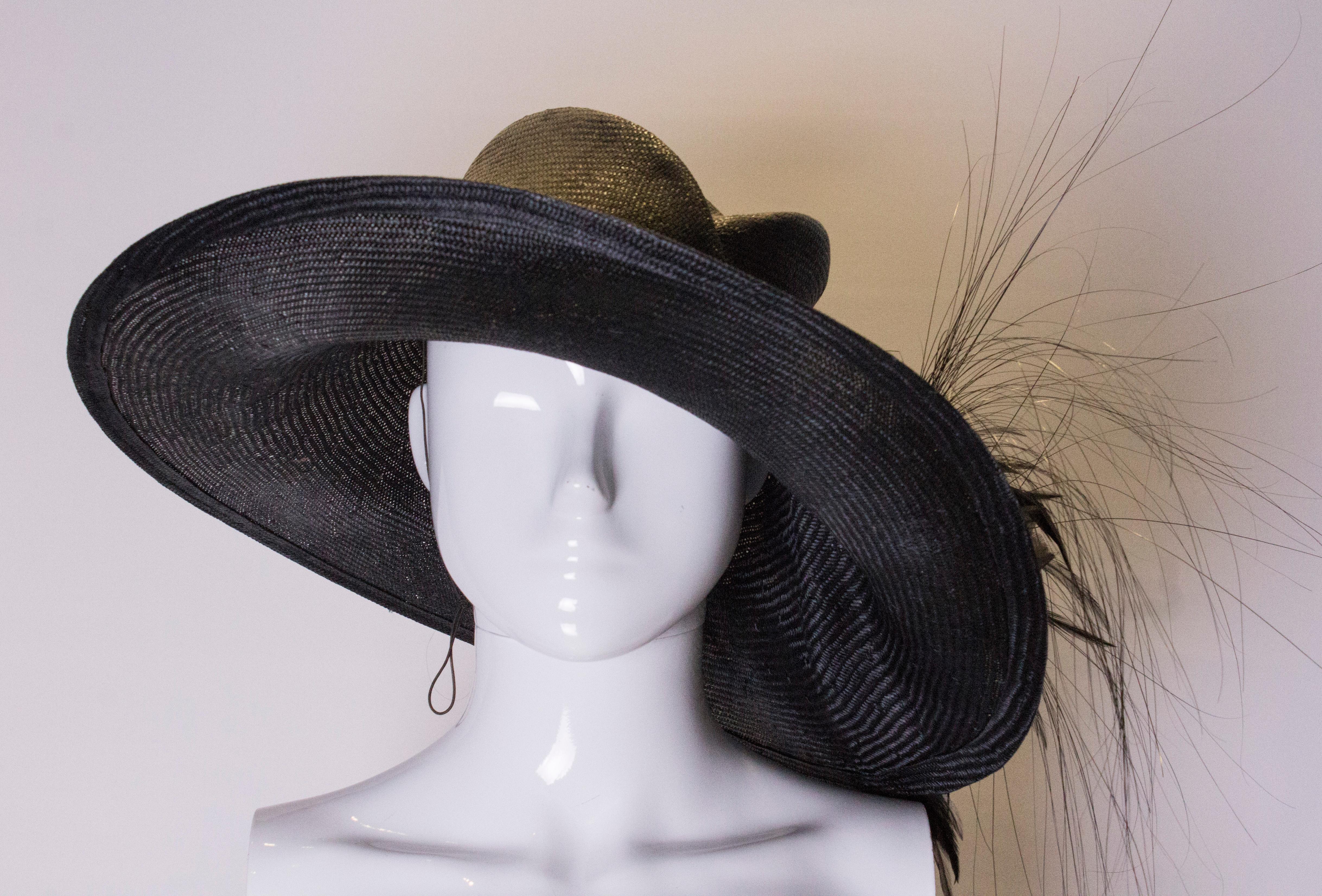 A head turning hat by Gabriela Ligenza. In black straw with feather and flower detail , the hat really does turn heads. Inner circumference 22''