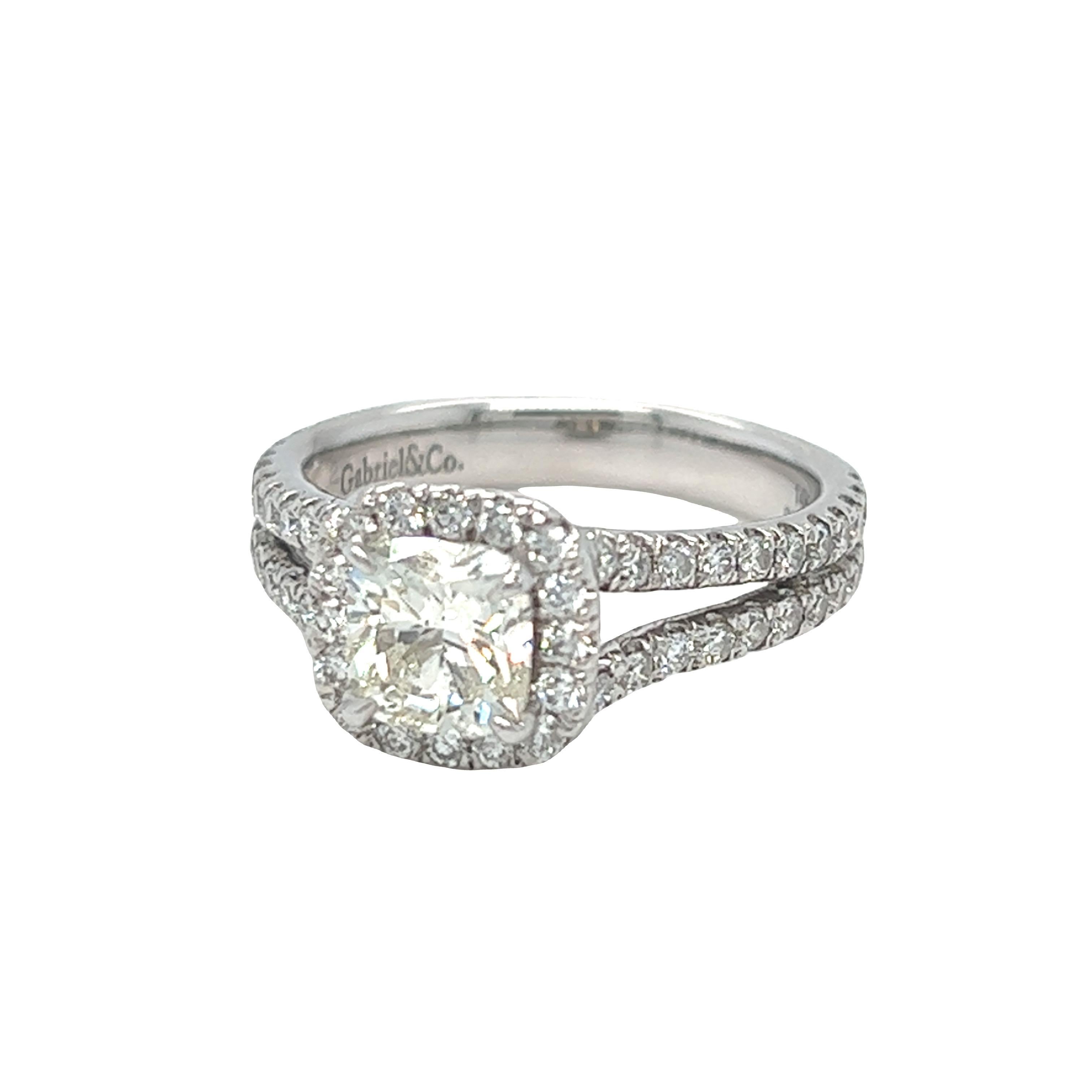 Modern classic cushion halo diamond engagement ring centers a beautiful cushion cut diamond, J color and SI1 clarity, weighing approximately 1.15 carat. The split shank setting and diamond peekaboo on either side adds a modern touch to the classic
