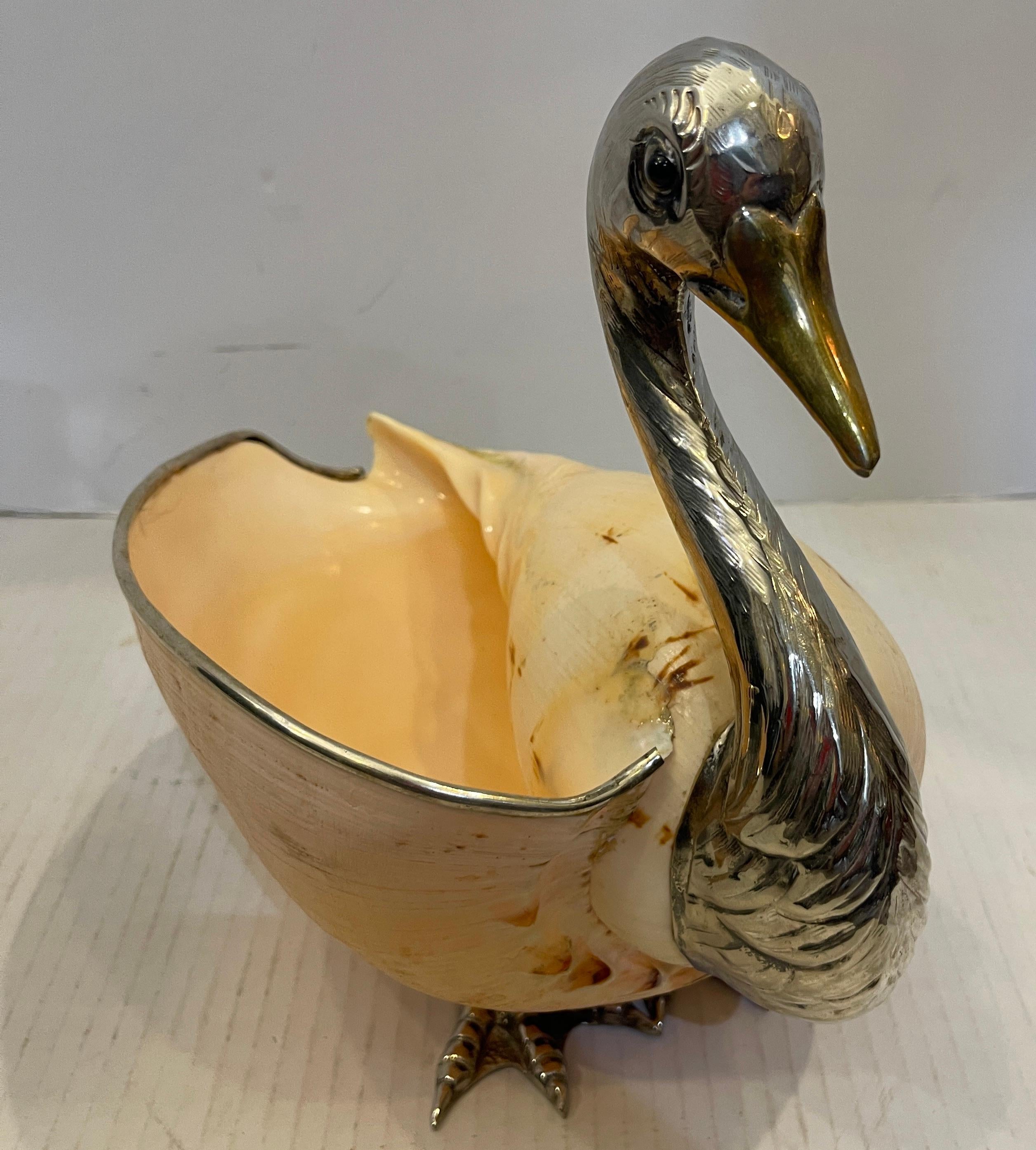 Nous venons de recevoir ce magnifique grand cygne italien en métal argenté et laiton noir avec un grand coquillage.
Cette figurine  La sculpture est de Gabriella Binazzi, mais n'est pas signée, A.I.C.,
Le bec en laiton et les yeux en émail sont très